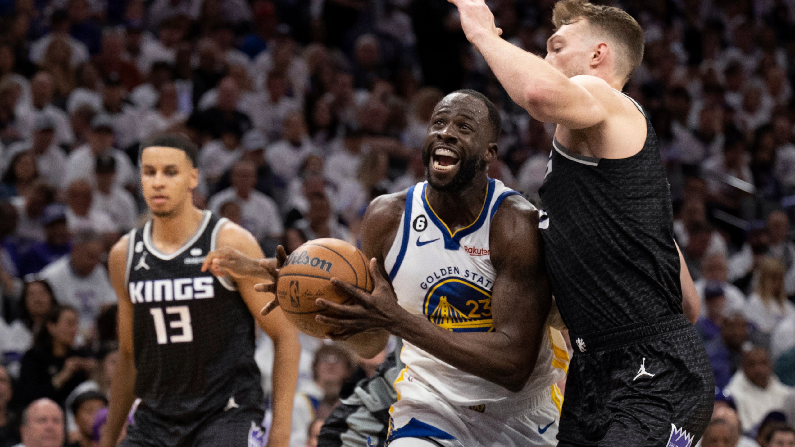 Golden State Warriors forward Draymond Green (23) is defended by Sacramento Kings forward Domantas Sabonis, right, during the second quarter of Game 1 of a first-round NBA basketball playoff series in Sacramento, Calif., Saturday, April 15, 2023. (AP Photo/José Luis Villegas)