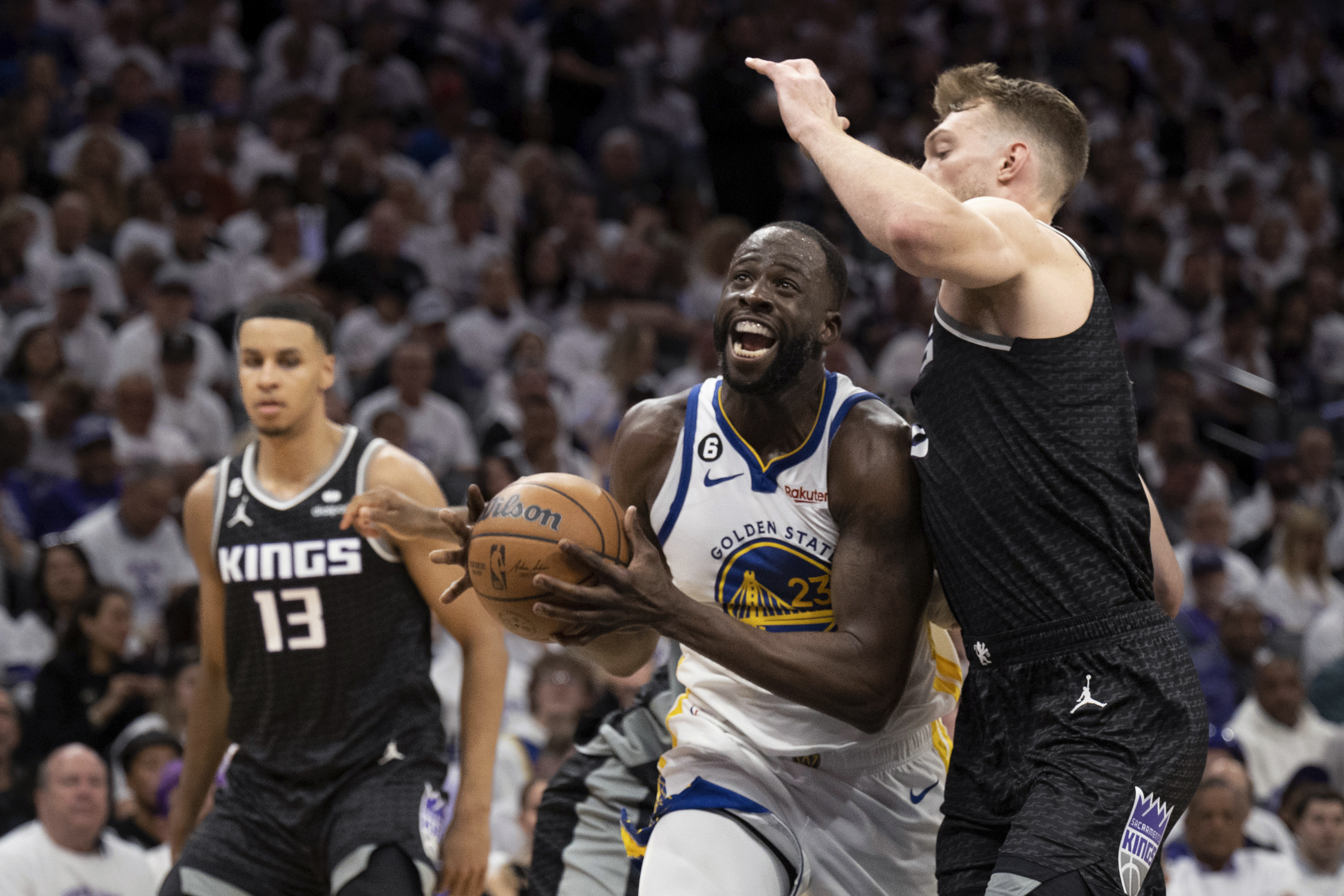 Golden State Warriors forward Draymond Green (23) is defended by Sacramento Kings forward Domantas Sabonis, right, during the second quarter of Game 1 of a first-round NBA basketball playoff series in Sacramento, Calif., Saturday, April 15, 2023. (AP Photo/José Luis Villegas)