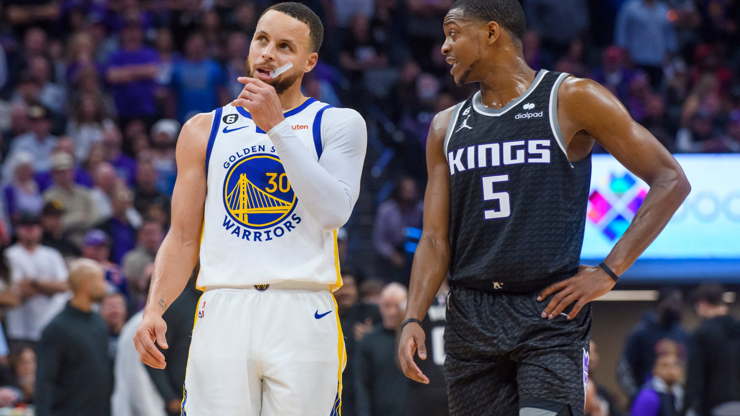 Golden State Warriors guard Stephen Curry (30) and Sacramento Kings guard De'Aaron Fox (5) talk during a timeout during the second half of Game 2 in the first round of the NBA basketball playoffs in Sacramento, Calif., Monday, April 17, 2023. The Kings won 114-106. (AP Photo/Randall Benton)