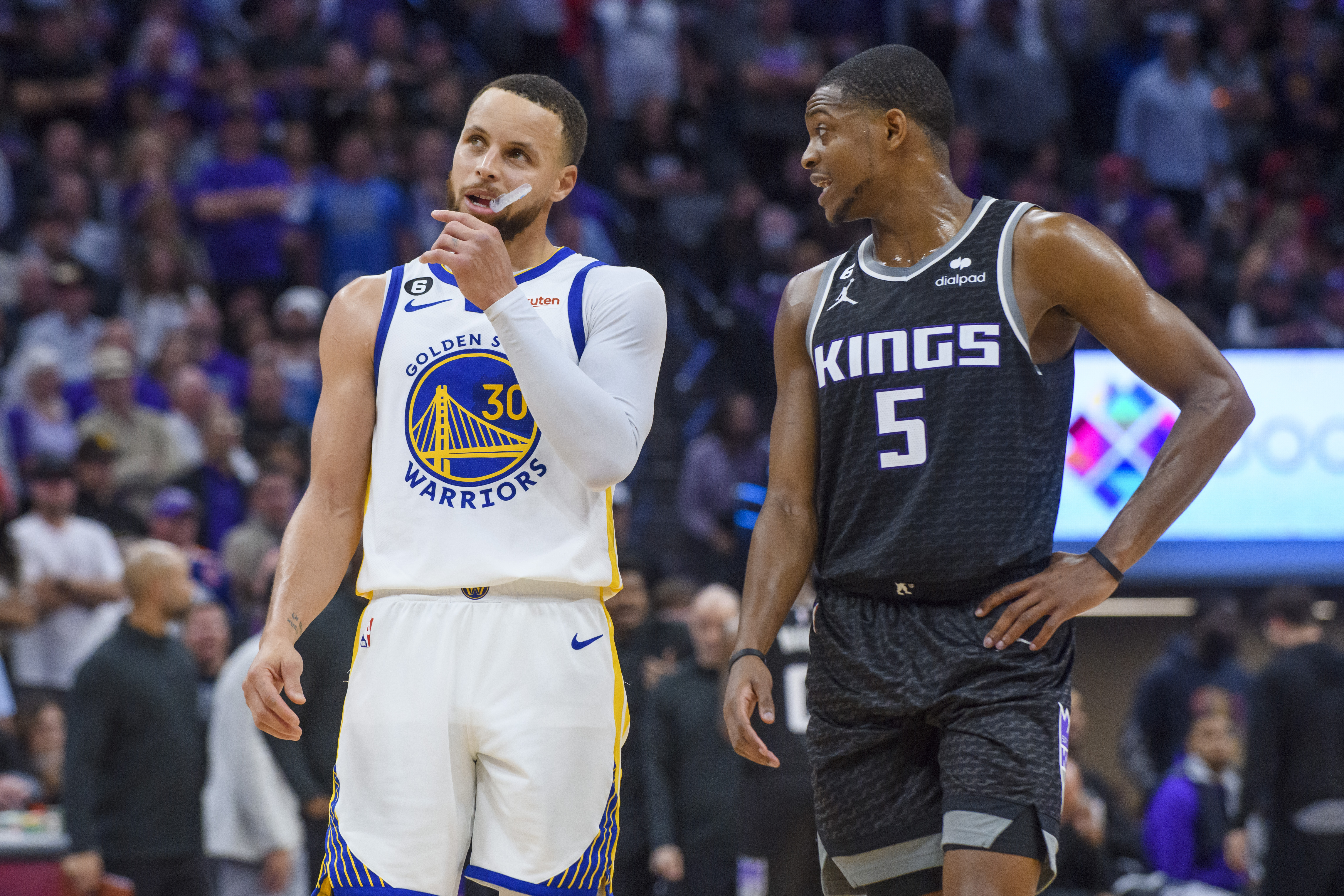 Golden State Warriors guard Stephen Curry (30) and Sacramento Kings guard De'Aaron Fox (5) talk during a timeout during the second half of Game 2 in the first round of the NBA basketball playoffs in Sacramento, Calif., Monday, April 17, 2023. The Kings won 114-106. (AP Photo/Randall Benton)