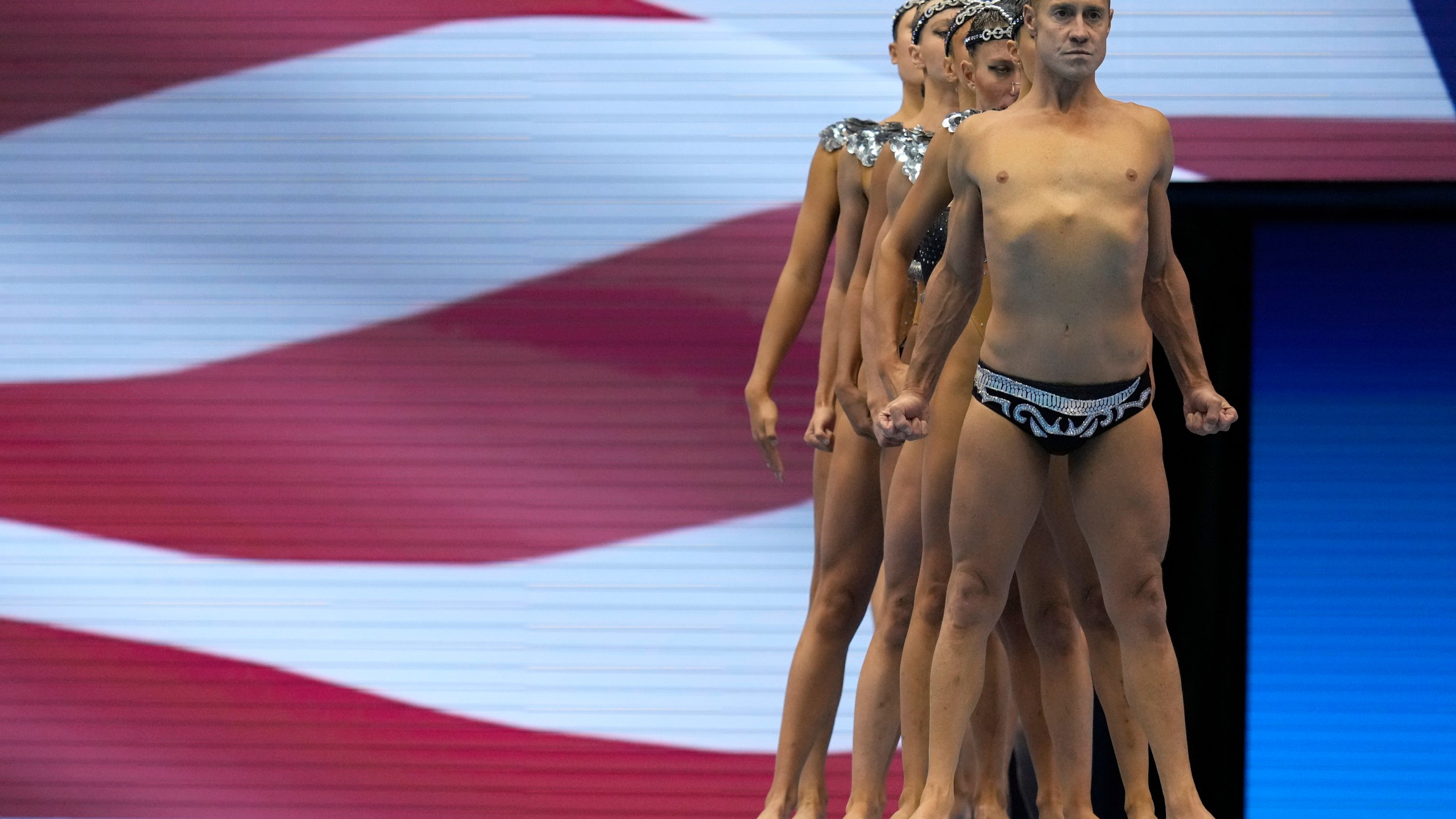 Bill May, front, leads the United States team out to compete in the team acrobatic of artistic swimming at the World Swimming Championships in Fukuoka, Japan, Saturday, July 15, 2023. Largely unnoticed by the general public, men have been participating in artistic swimming, formerly known as synchronized swimming, for decades. (AP Photo/Nick Didlick)