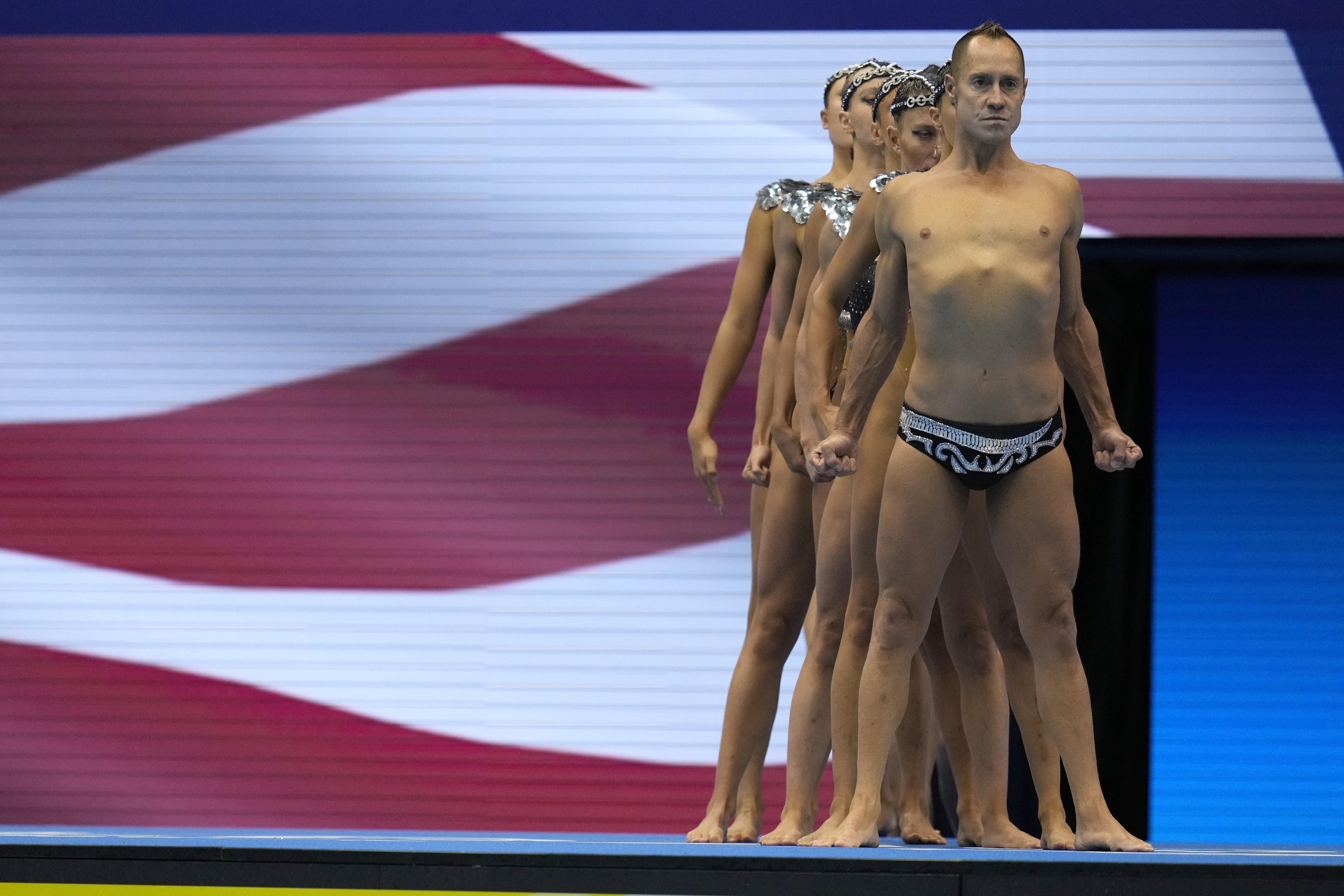 Bill May, front, leads the United States team out to compete in the team acrobatic of artistic swimming at the World Swimming Championships in Fukuoka, Japan, Saturday, July 15, 2023. Largely unnoticed by the general public, men have been participating in artistic swimming, formerly known as synchronized swimming, for decades. (AP Photo/Nick Didlick)