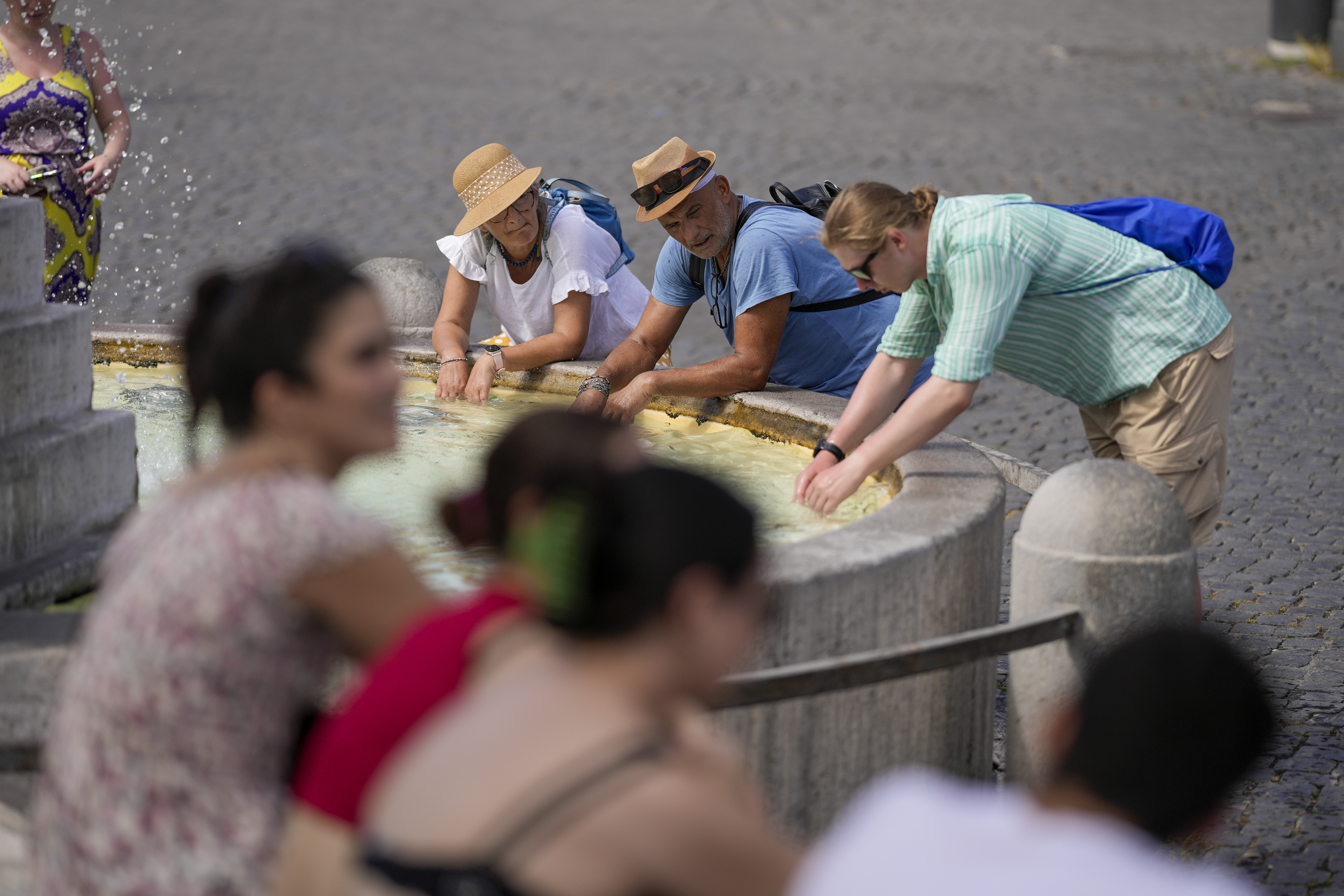 Tourists cool off at a fountain as they visit Rome, Saturday, July 22, 2023. An intense heat wave has reached Italy, bringing temperatures close to 40 degrees Celsius in many cities across the country. (AP Photo/Andrew Medichini)