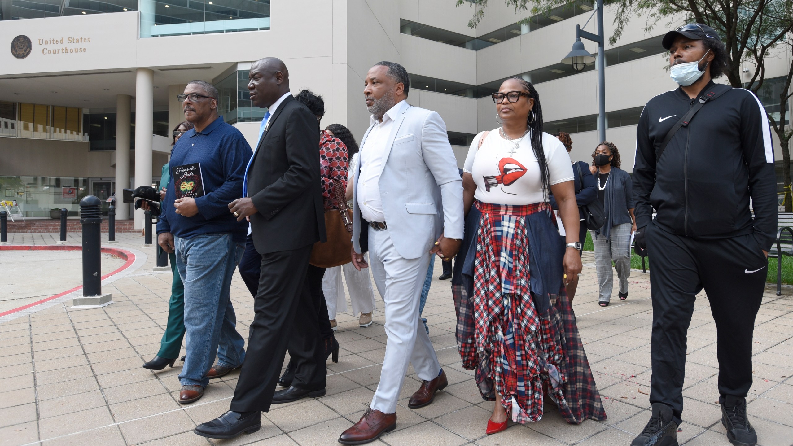 FILE - Attorney Ben Crump, second from left, walks with Ron Lacks, left, Alfred Lacks Carter, third from left, both grandsons of Henrietta Lacks, and other descendants of Lacks, outside the federal courthouse in Baltimore, Oct. 4, 2021. The family of Henrietta Lacks is settling a lawsuit against a biotechnology company it accuses of improperly profiting from her cells. Their federal lawsuit in Baltimore claimed Thermo Fisher Scientific has made billions from tissue taken without the Black woman’s consent from her cervical cancer tumor. (AP Photo/Steve Ruark, file)