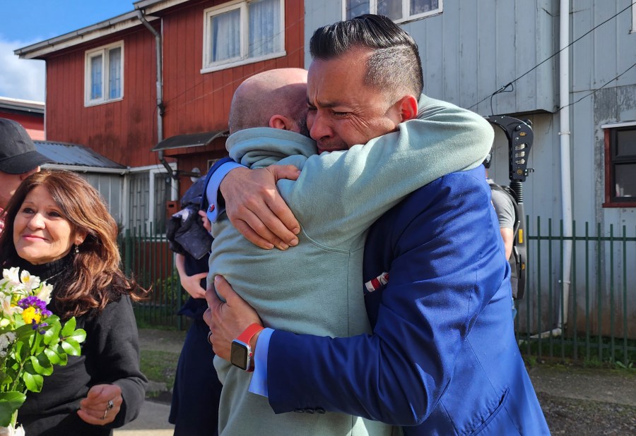 In this image provided by Constanza Del Rio/Nos Buscamos, Jimmy Thyden, right, hugs his brother Pablo Leiva Gonzalez as Maria Angelica Gonzalez, his Chilean birth mother, left, looks on in Valdivia, Chile on Aug. 17, 2023. Thyden got to embrace his birth mother for the first time during the long-awaited family reunion in Valdivia. For months Thyden has been on a journey to uncover the mysteries of his counterfeit adoption, and to reconnect with his biological mother, brothers and sister. (Constanza Del Rio/Nos Buscamos via AP)