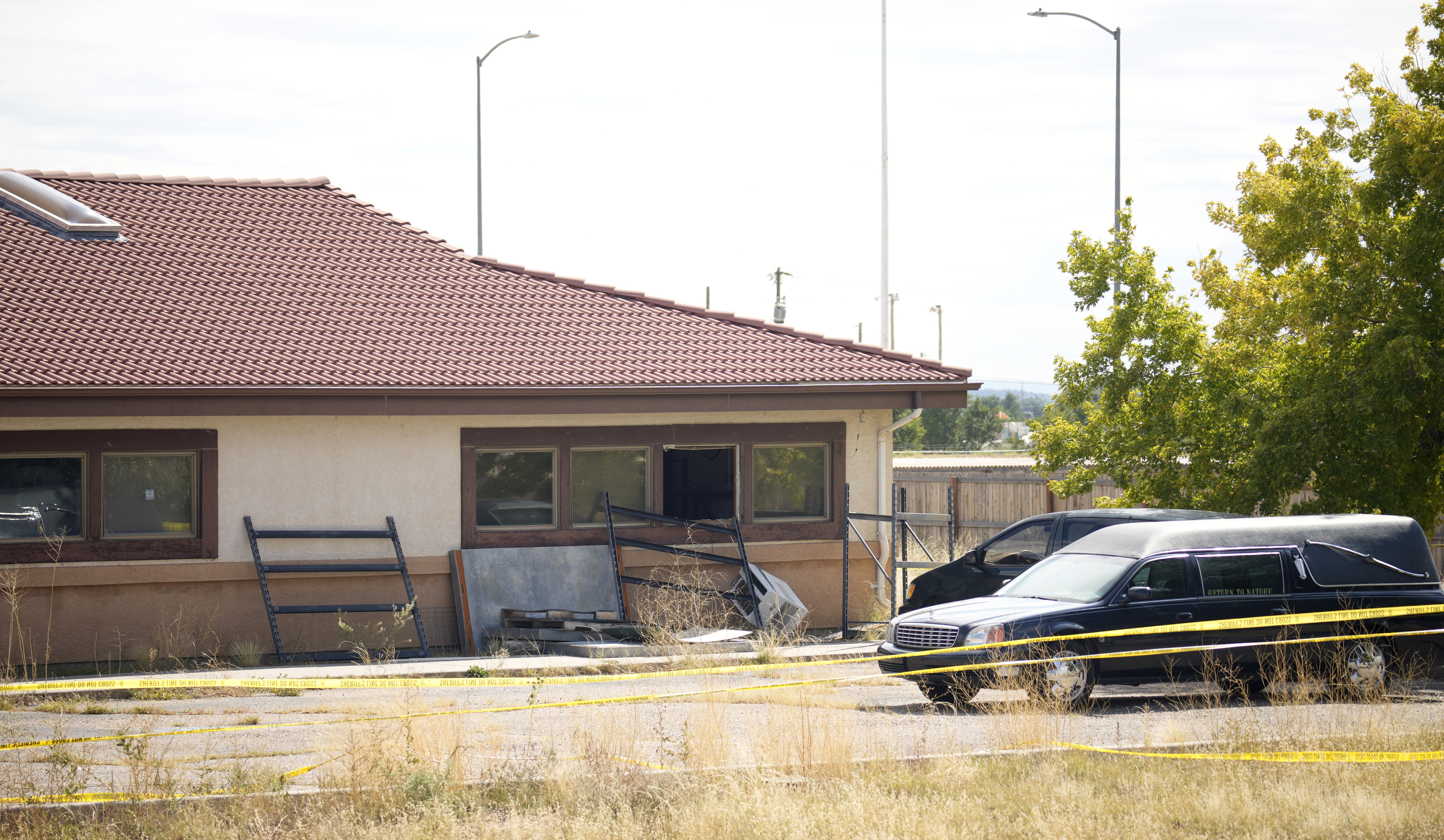 FILE - A hearse and van sit outside the Return to Nature Funeral Home, Oct. 6, 2023, in Penrose, Colo. Investigators who entered the funeral home encountered stacks of partially covered human remains, bodily fluids several inches deep on the floor and flies, an FBI agent testified Thursday, Jan. 11, 2024. (AP Photo/David Zalubowski, File)