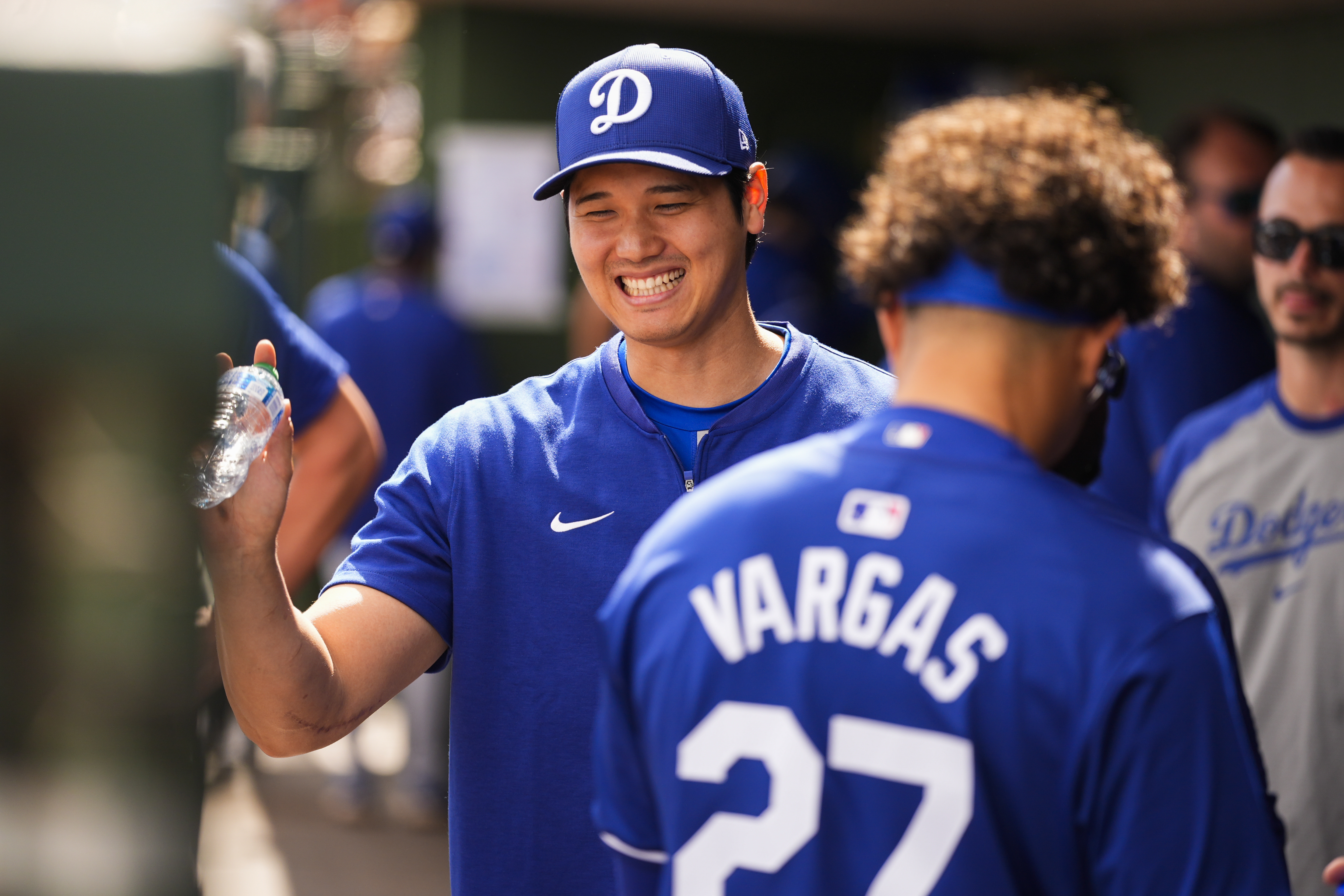 Los Angeles Dodgers' Shohei Ohtani laughs in the dugout before a spring training baseball game against the Texas Rangers, Wednesday, Feb. 28, 2024, in Surprise, Ariz. (AP Photo/Lindsey Wasson)