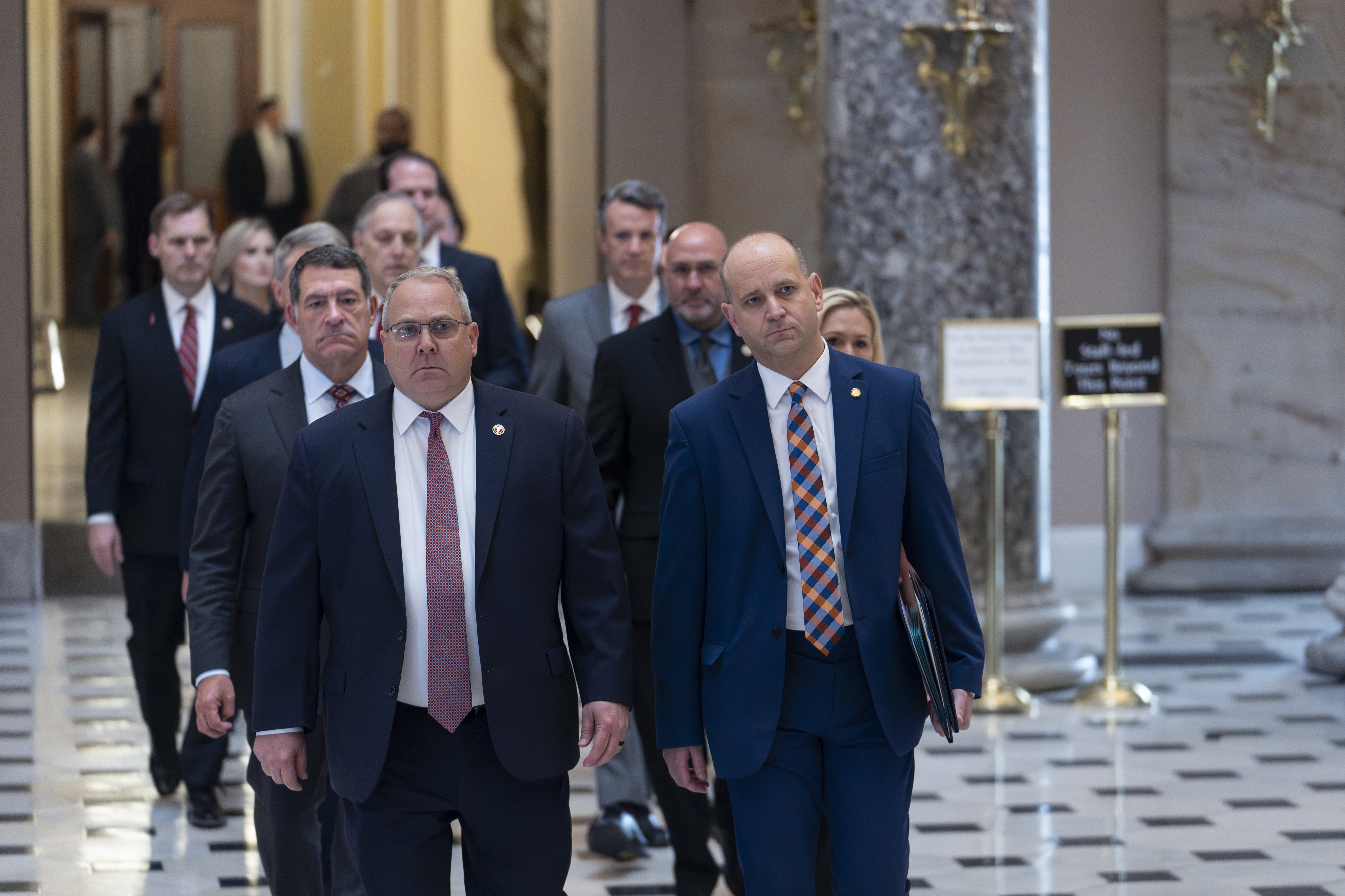 House Republicans, escorted by House Sergeant-at-Arms William McFarland, left, and Acting-Clerk of the House Kevin McCumber, right, walk to the Senate as they deliver the articles of impeachment against Homeland Security Secretary Alejandro Mayorkas, at the Capitol in Washington, Tuesday, April 16, 2024. (AP Photo/J. Scott Applewhite)