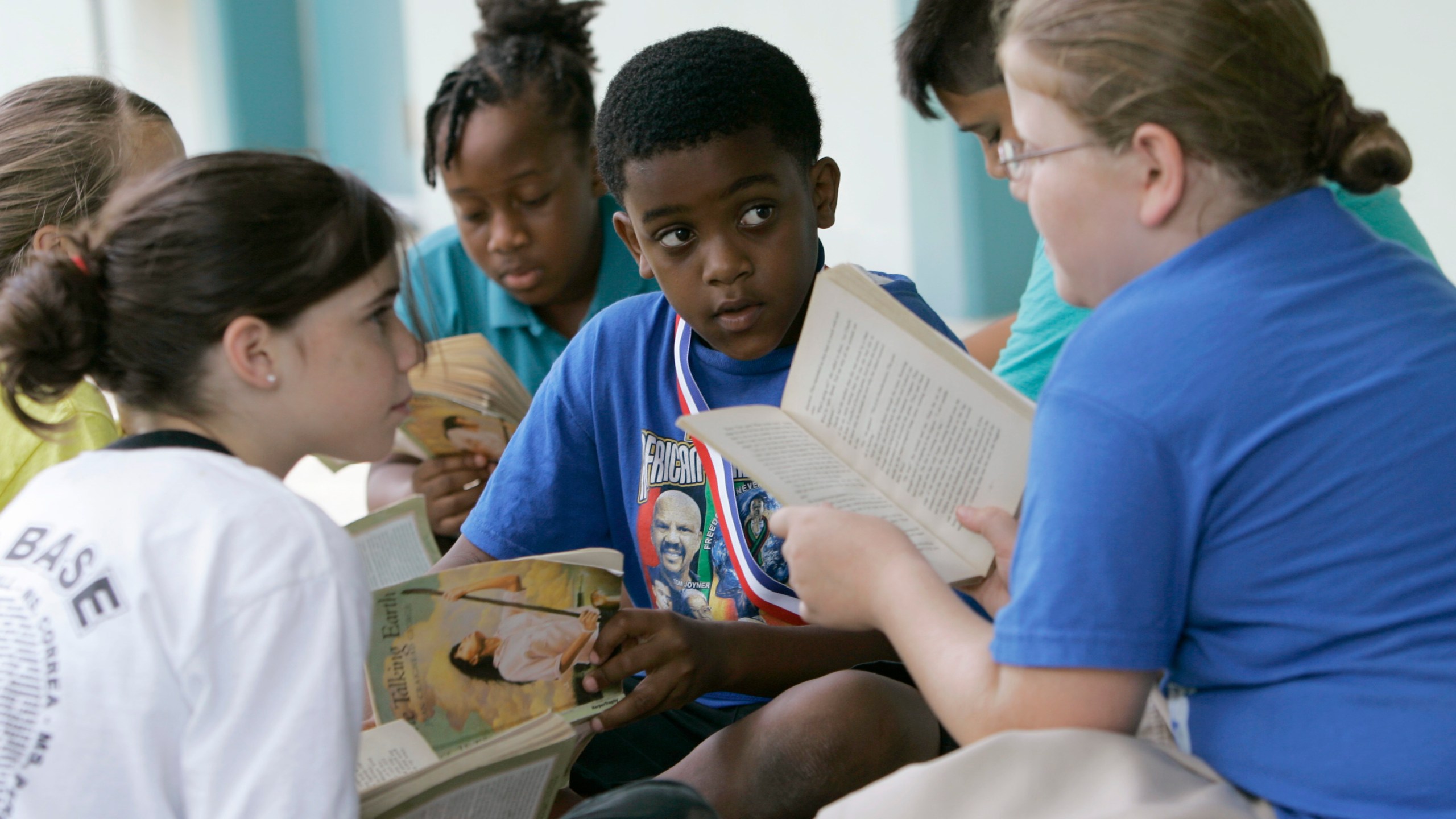 FILE - Joseph Webb, center; Kristina Carr, right; and Kaelyn Korovich, left, read outside their classroom at Air Base Elementary School, June 4, 2009, in Homestead, Fla. The school was one of the first in Miami-Dade County to integrate Black students. Friday, May 17, 2024, marks 70 years since the U.S. Supreme Court ruled that separating children in schools by race was unconstitutional. On paper, Brown v. Board of Education still stands. In reality, school integration is all but gone, the victim of a gradual series of court cases that slowly eroded it, leaving little behind. (AP Photo/Wilfredo Lee, File)