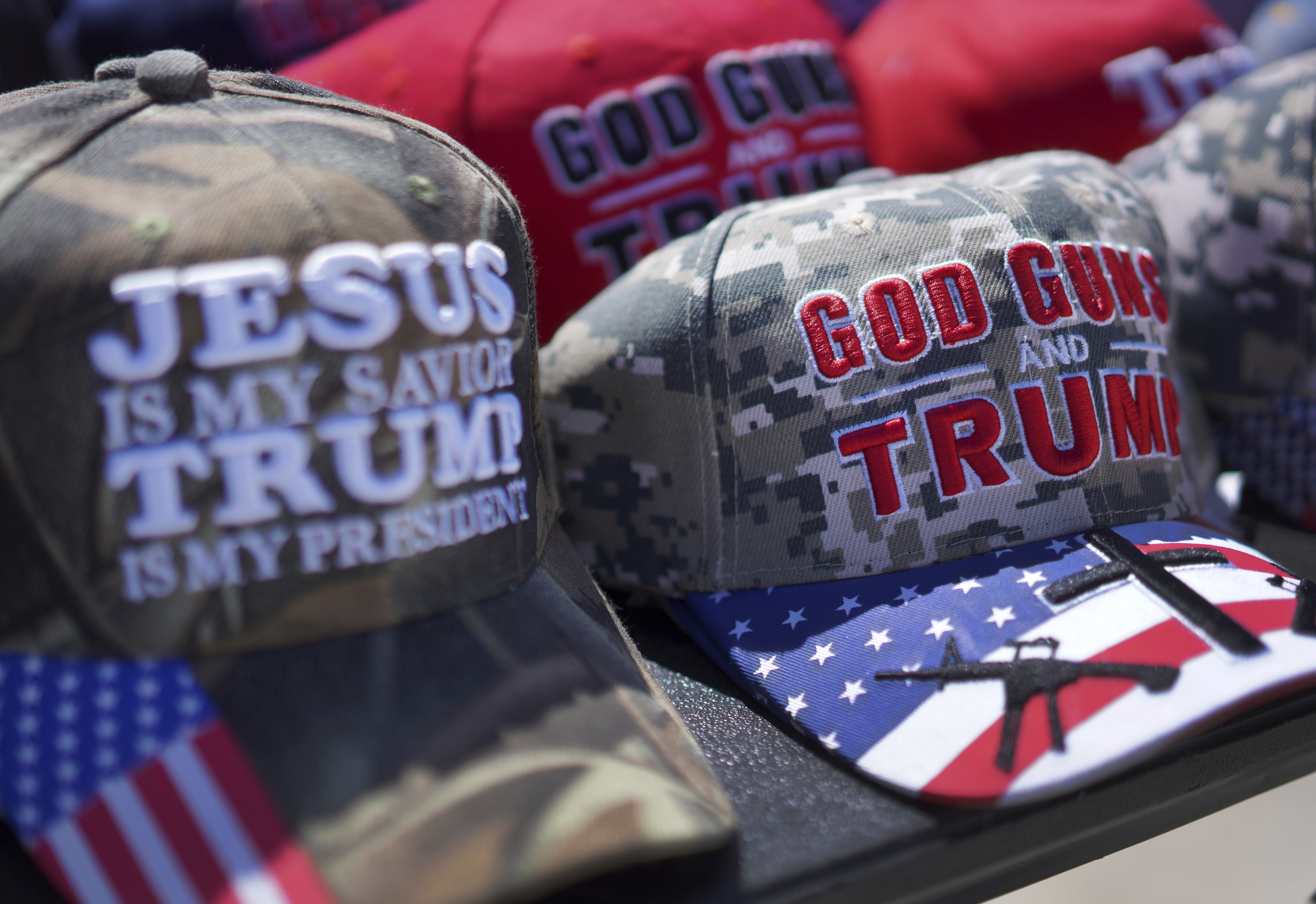 Hats reading, "God, Guns and Trump," and "Jesus is my savior, Trump is my president," are sold at a campaign rally for former president Donald Trump in Vandalia, Ohio, on Saturday, March 16, 2024. Trump, who is coasting into a third Republican presidential nomination, continues to draw strong support from evangelicals and other conservative Christians. (AP Photo/Jessie Wardarski)