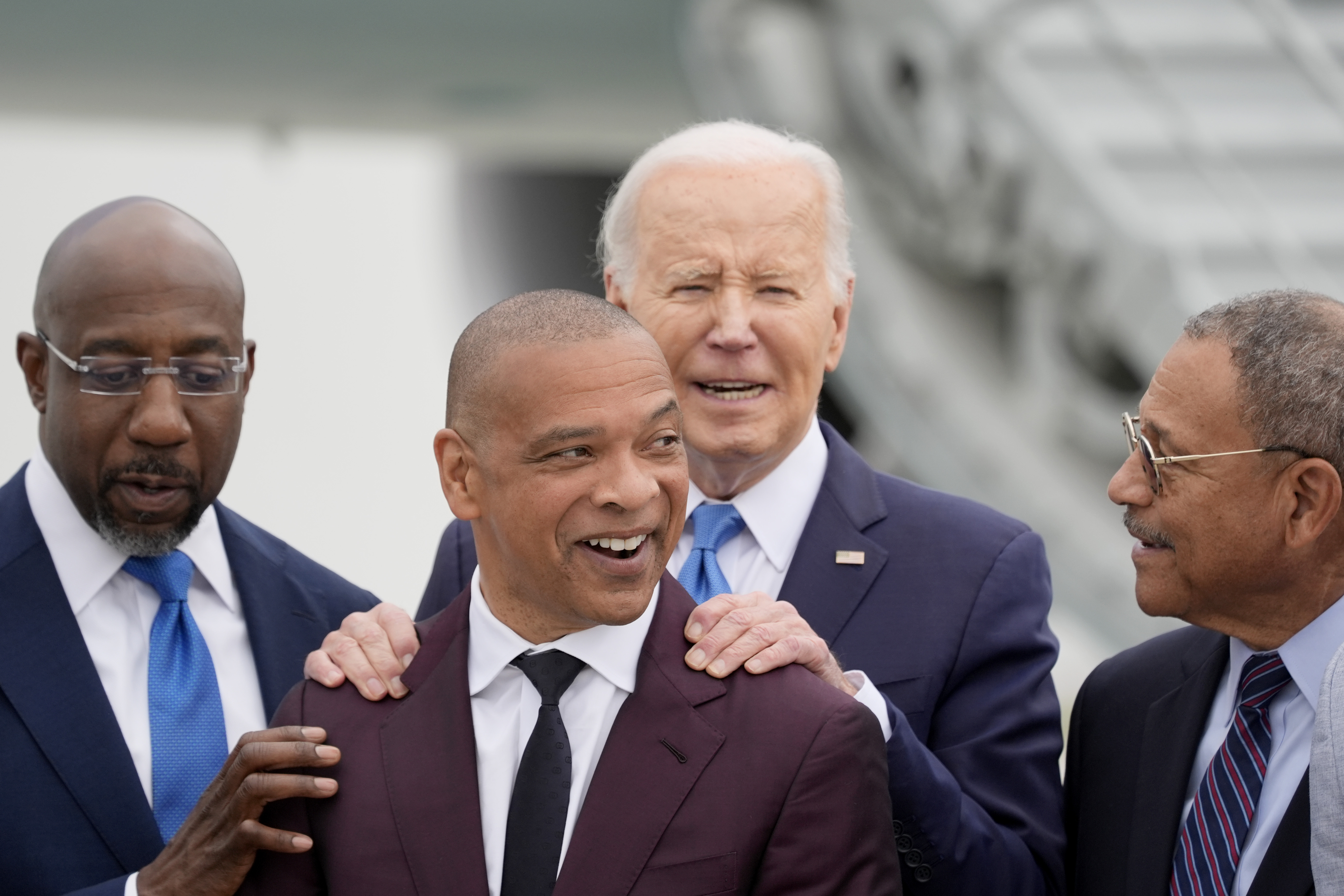 President Joe Biden, second from right, is greeted by alumni of Morehouse College including Sen. Raphael Warnock, D-Ga., from left, Marlon Kimpson, a member of the advisory committee for trade policy and negotiations in the office of the U.S. Trade Representative, and Rep. Sanford Bishop, D-Ga., upon arriving at Hartsfield-Jackson Atlanta International Airport, Saturday, May 18, 2024, in Atlanta. (AP Photo/Alex Brandon)