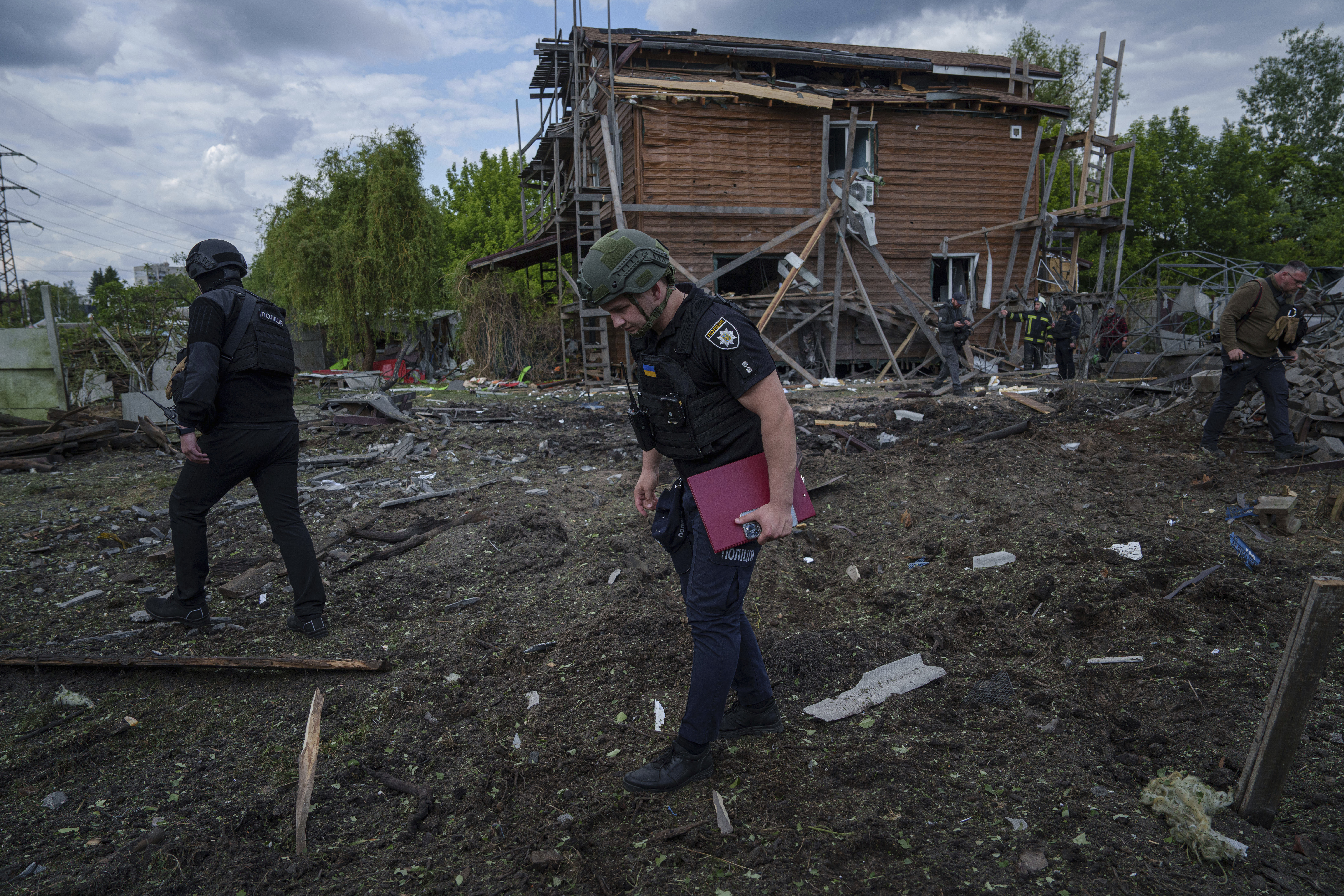 Ukrainian police officers look for fragments of a glide bomb in front of damaged house after a Russian airstrike on a residential neighbourhood in Kharkiv, Ukraine, Saturday, May 18, 2024. (AP Photo/Evgeniy Maloletka)
