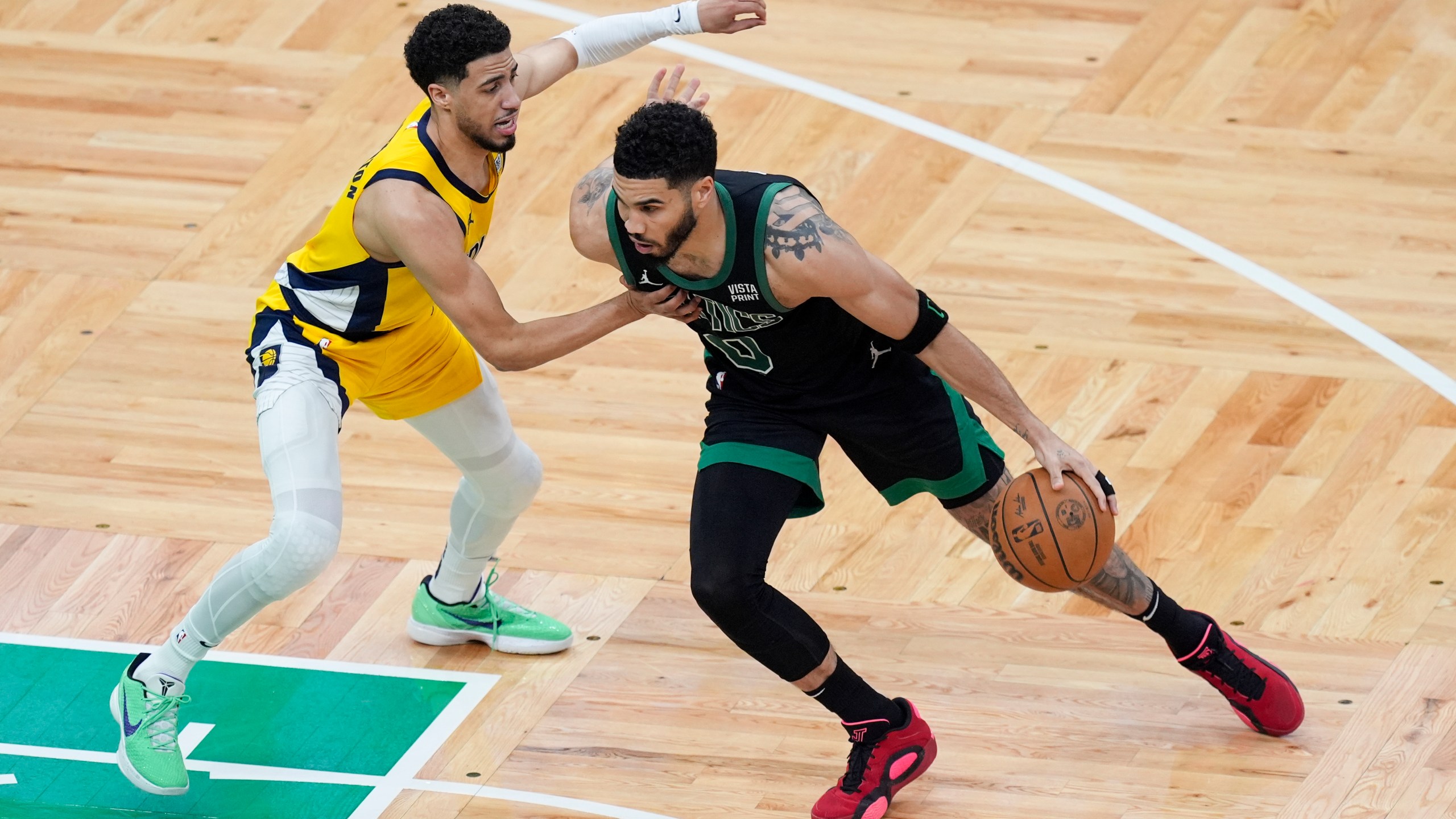 Boston Celtics forward Jayson Tatum (0) is defended by Indiana Pacers guard Tyrese Haliburton, left, during the first half of Game 2 of the NBA Eastern Conference basketball finals Thursday, May 23, 2024, in Boston. (AP Photo/Michael Dwyer)