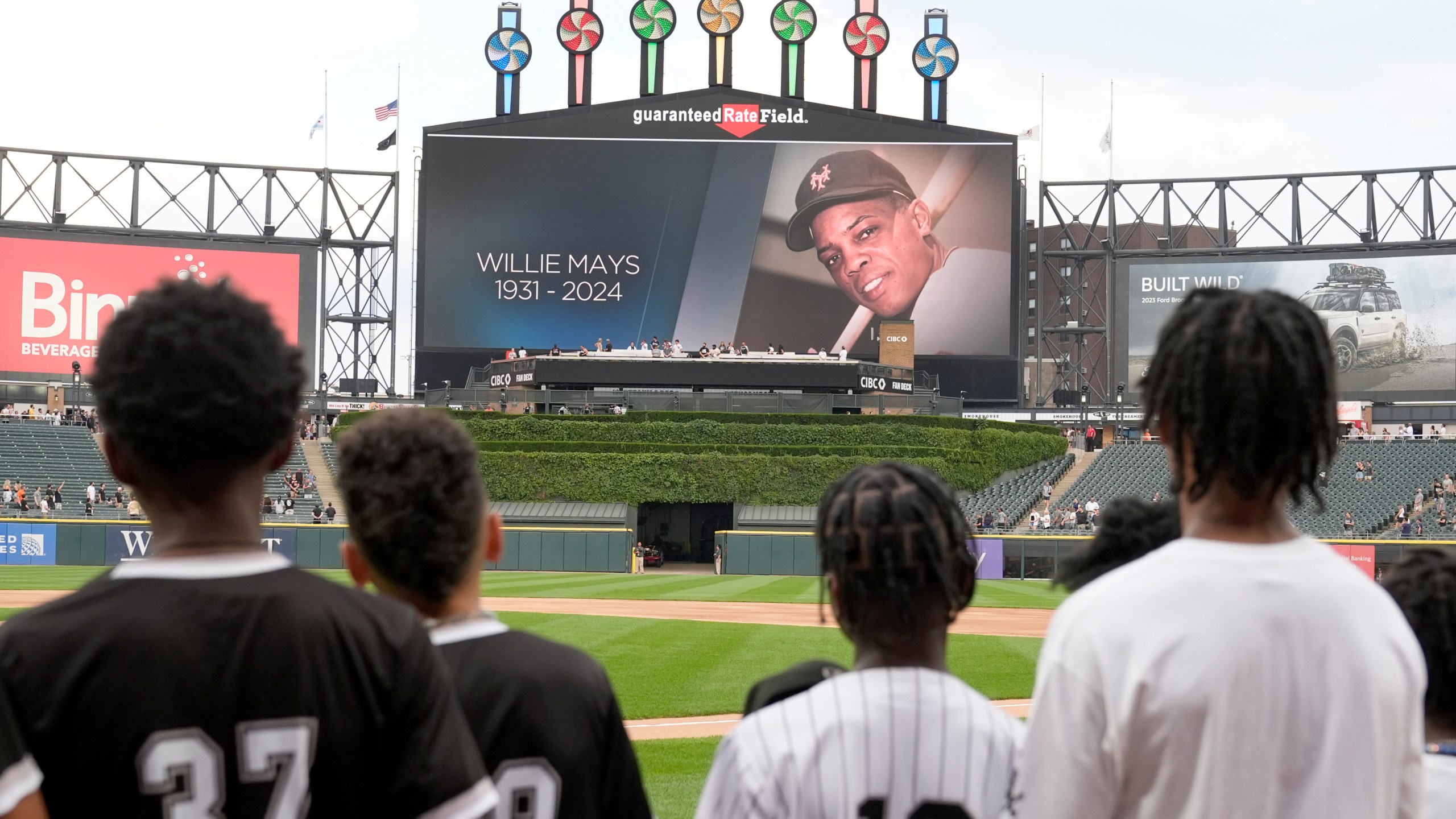 Members of the Chicago White Sox's Youth Baseball League stand during a moment of silence for Willie Mays, who died Tuesday, before a baseball game between the White Sox and the Houston Astros on Wednesday, June 19, 2024, in Chicago. (AP Photo/Charles Rex Arbogast)