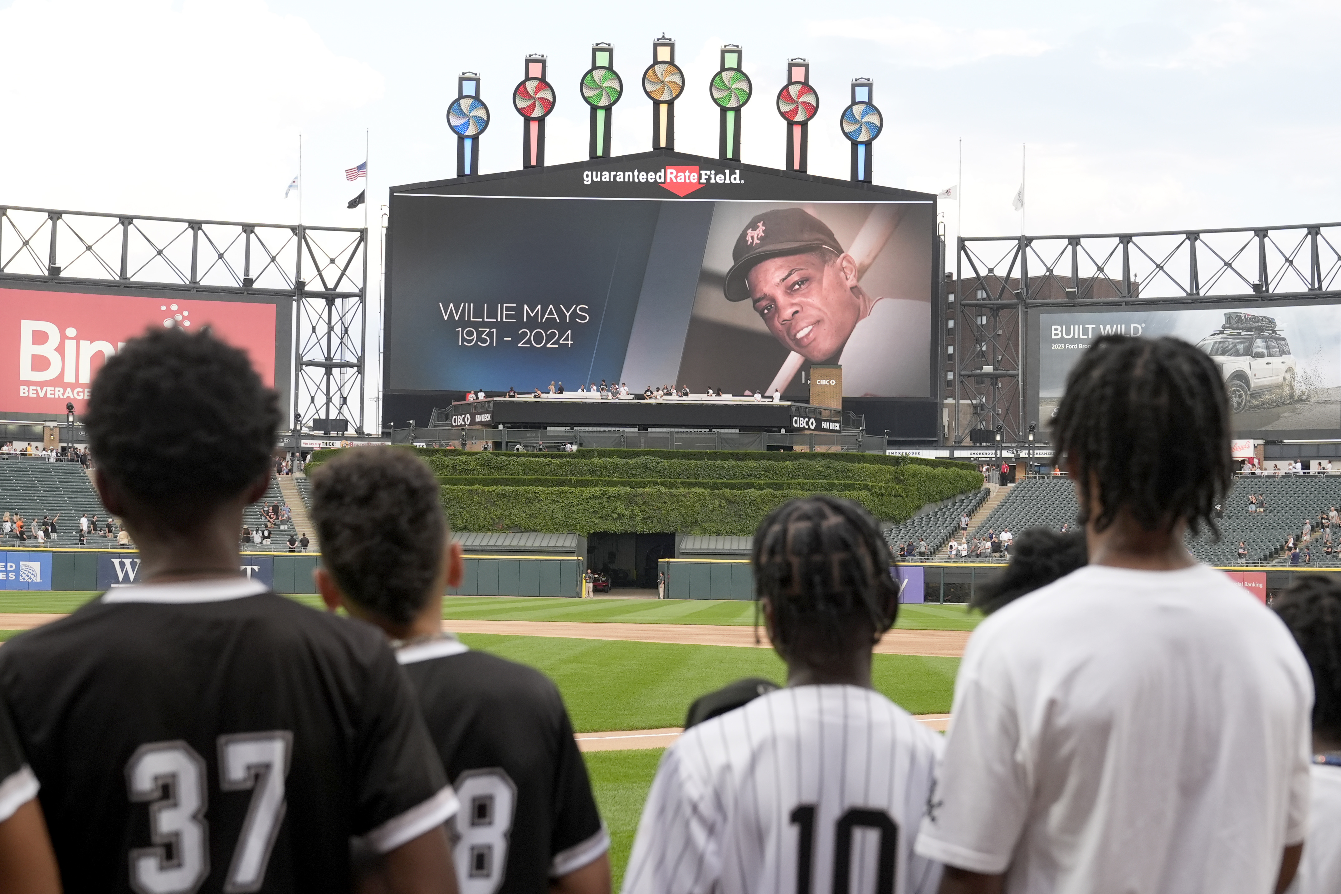 Members of the Chicago White Sox's Youth Baseball League stand during a moment of silence for Willie Mays, who died Tuesday, before a baseball game between the White Sox and the Houston Astros on Wednesday, June 19, 2024, in Chicago. (AP Photo/Charles Rex Arbogast)