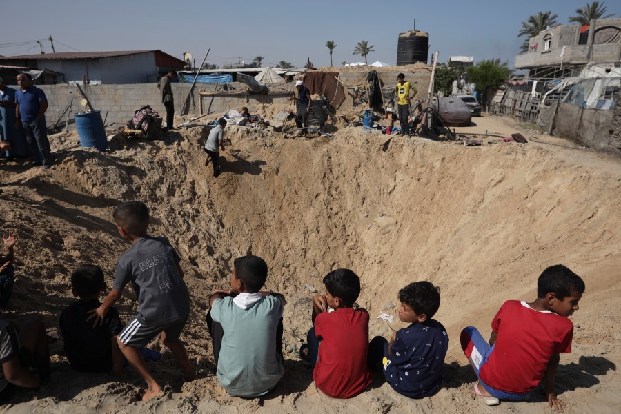 Palestinian children sit at the edge of a crater after an Israeli airstrike in Khan Younis, southern Gaza Strip, Friday, June 21, 2024. (AP Photo /Jehad Alshrafi)