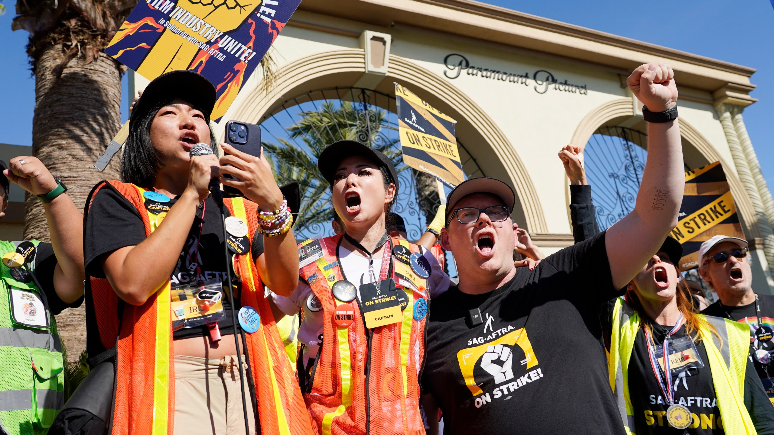 FILE - SAG-AFTRA captains Iris Liu, left, and Miki Yamashita, center, and SAG-AFTRA chief negotiator Duncan Crabtree-Ireland lead a cheer for striking actors outside Paramount Pictures studio, Nov. 3, 2023, in Los Angeles. While negotiators with SAG-AFTRA have made gains in bargaining over wages and job safety in their video game contract, leaders say talks have stalled over a key issue: protections over the use of artificial intelligence. (AP Photo/Chris Pizzello, File)