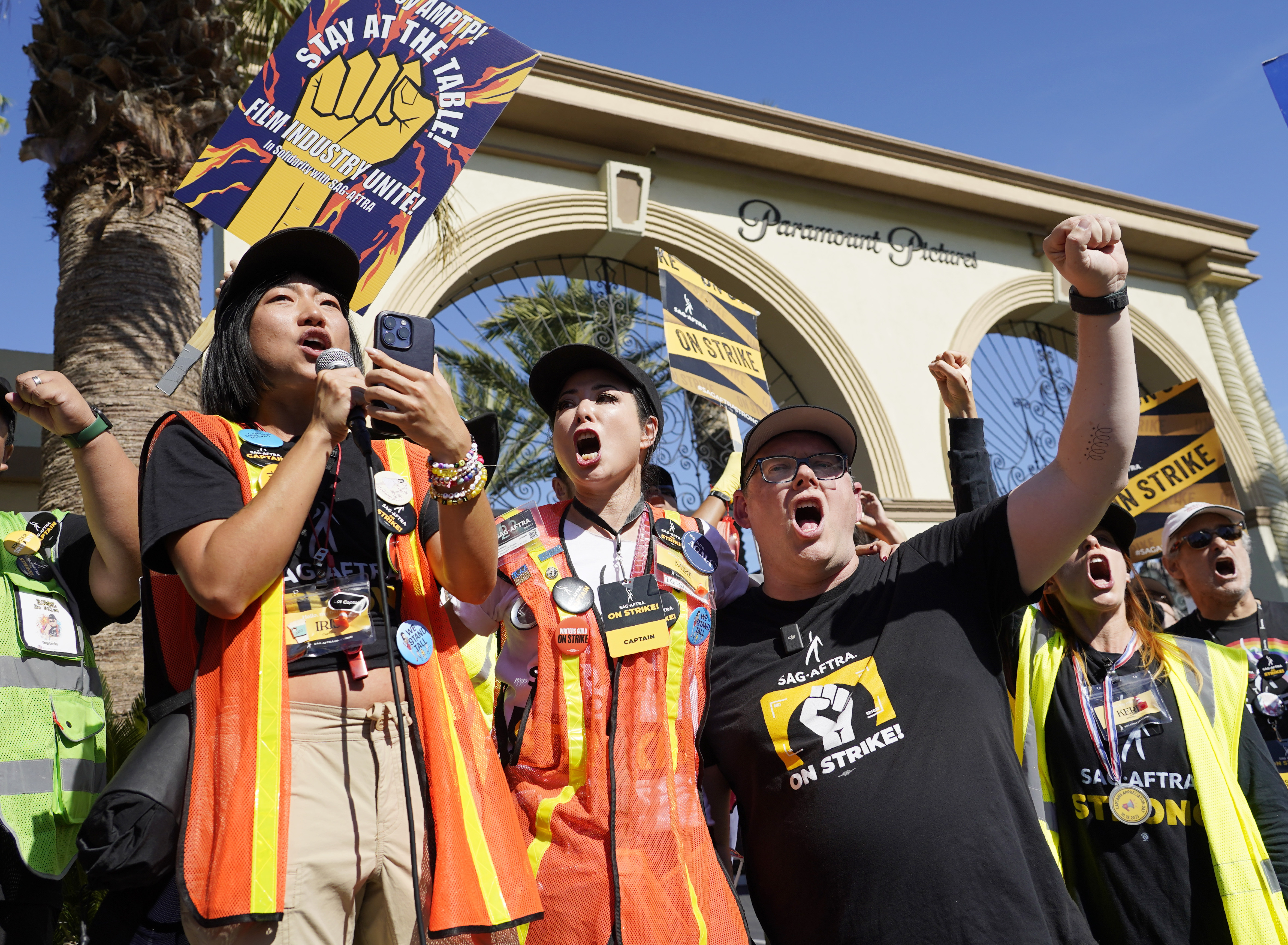 FILE - SAG-AFTRA captains Iris Liu, left, and Miki Yamashita, center, and SAG-AFTRA chief negotiator Duncan Crabtree-Ireland lead a cheer for striking actors outside Paramount Pictures studio, Nov. 3, 2023, in Los Angeles. While negotiators with SAG-AFTRA have made gains in bargaining over wages and job safety in their video game contract, leaders say talks have stalled over a key issue: protections over the use of artificial intelligence. (AP Photo/Chris Pizzello, File)