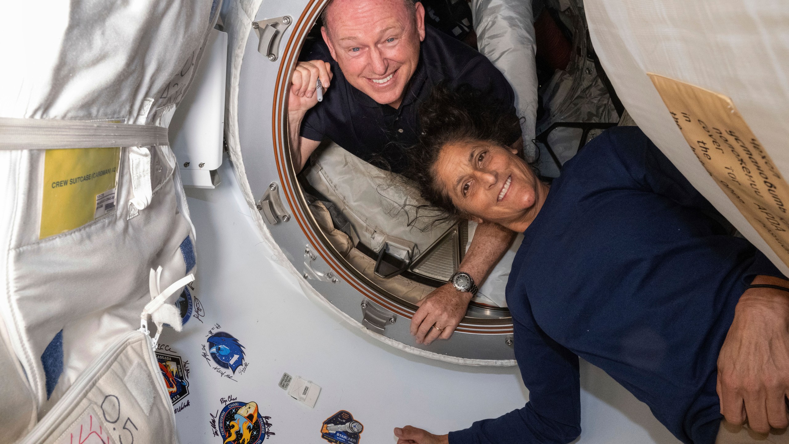 In this photo provided by NASA, Boeing Crew Flight Test astronauts Butch Wilmore, left, and Suni Williams pose for a portrait inside the vestibule between the forward port on the International Space Station's Harmony module and Boeing's Starliner spacecraft on June 13, 2024. (NASA via AP)