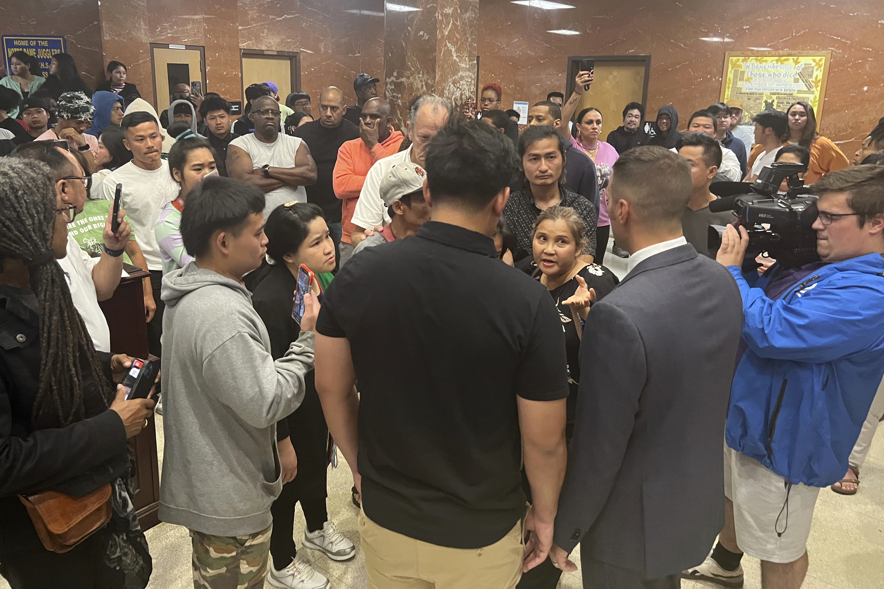 Utica Mayor Michael Galime, center right, grey jacket, talks with the family members of a 13-year-old boy who was fatally shot by a police officer Friday night after a news conference, Saturday, June 28, 2024 in Utica, N.Y. An officer shot and killed the teenager who was fleeing while wielding a “realistic appearing firearm," authorities said Saturday. (Kenny Lacy Jr./Syracuse.com via AP)