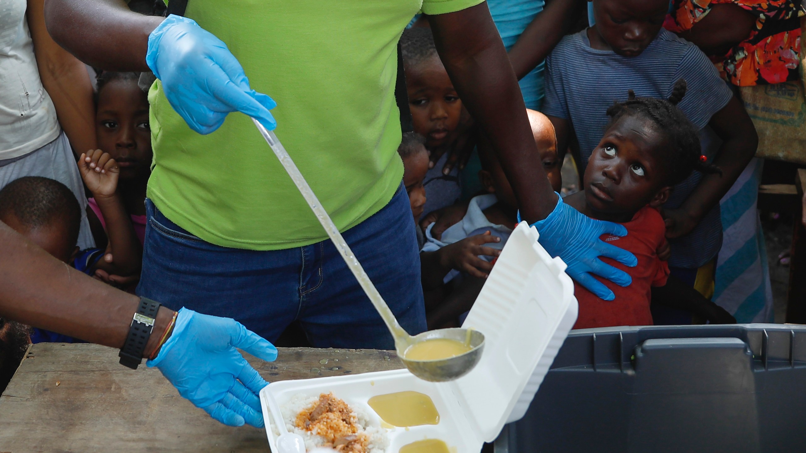 FILE - A server ladles soup into a container as children line up to receive food at a shelter for families displaced by gang violence, in Port-au-Prince, Haiti, March 14, 2024. Gang violence in Haiti has displaced over 300,000 children since March, according to a new report from the U.N. children's agency released late Tuesday, July 2, as the Caribbean country struggles to curb killings and kidnappings. (AP Photo/Odelyn Joseph, File)