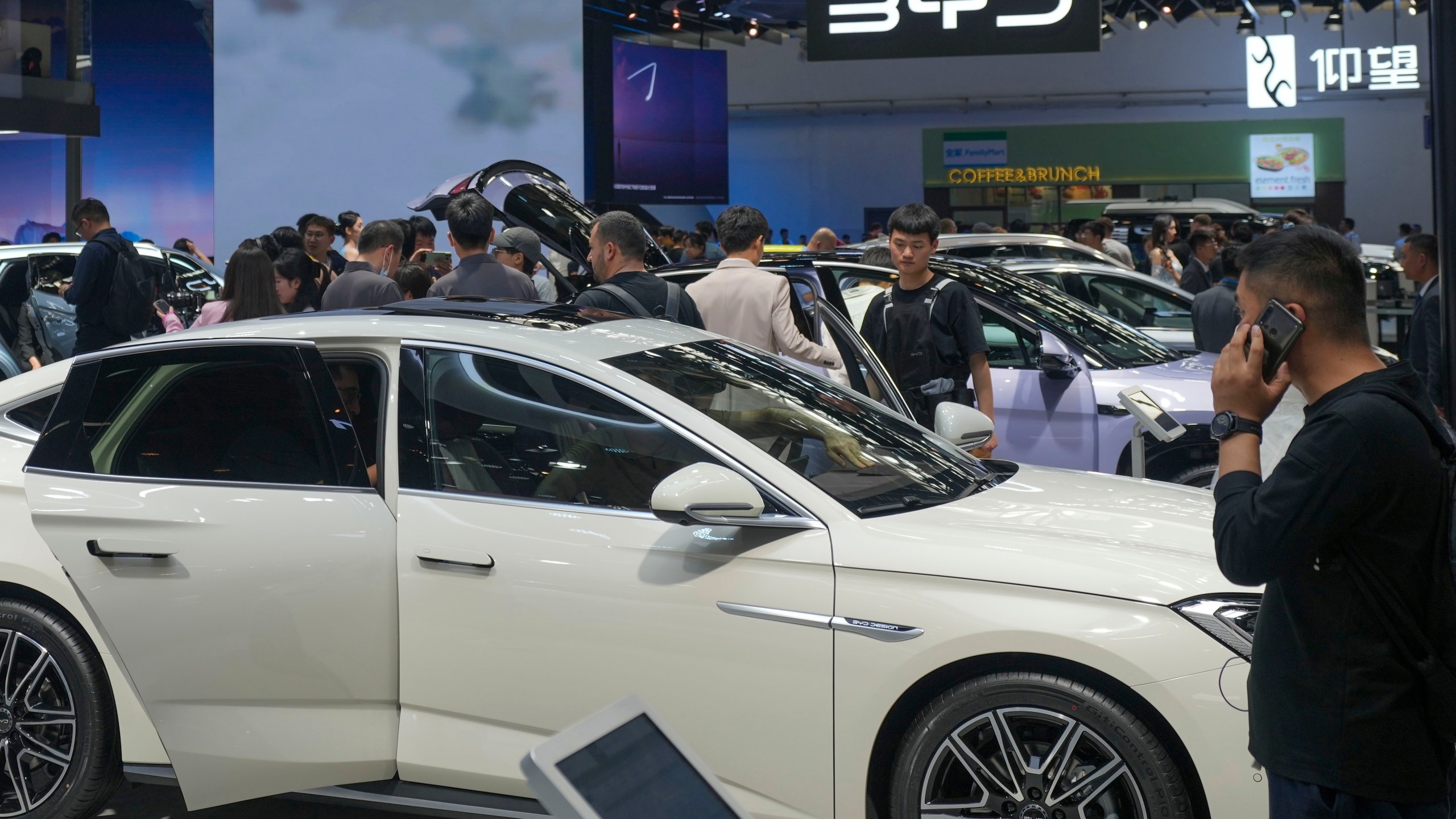 FILE - Visitors look at cars at the BYD booth during the China Auto Show in Beijing, China, Friday, April 26, 2024. The European Union threatened on Wednesday, june 12, 2024, to hike tariffs on Chinese electric vehicles, escalating a trade dispute over Beijing's subsidies for the exports that Brussels worries is hurting domestic automakers. (AP Photo/Tatan Syuflana, File)