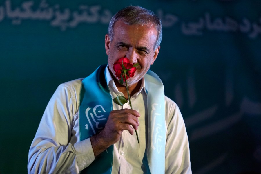 Reformist candidate for the Iran's presidential election Masoud Pezeshkian smells a flower during a campaign rally in Tehran, Iran, Wednesday, July 3, 2024. Comments suggesting that Iran's reformist presidential candidate could increase government-set gasoline prices have raised fears of a repeat of nationwide protests. (AP Photo/Vahid Salemi)