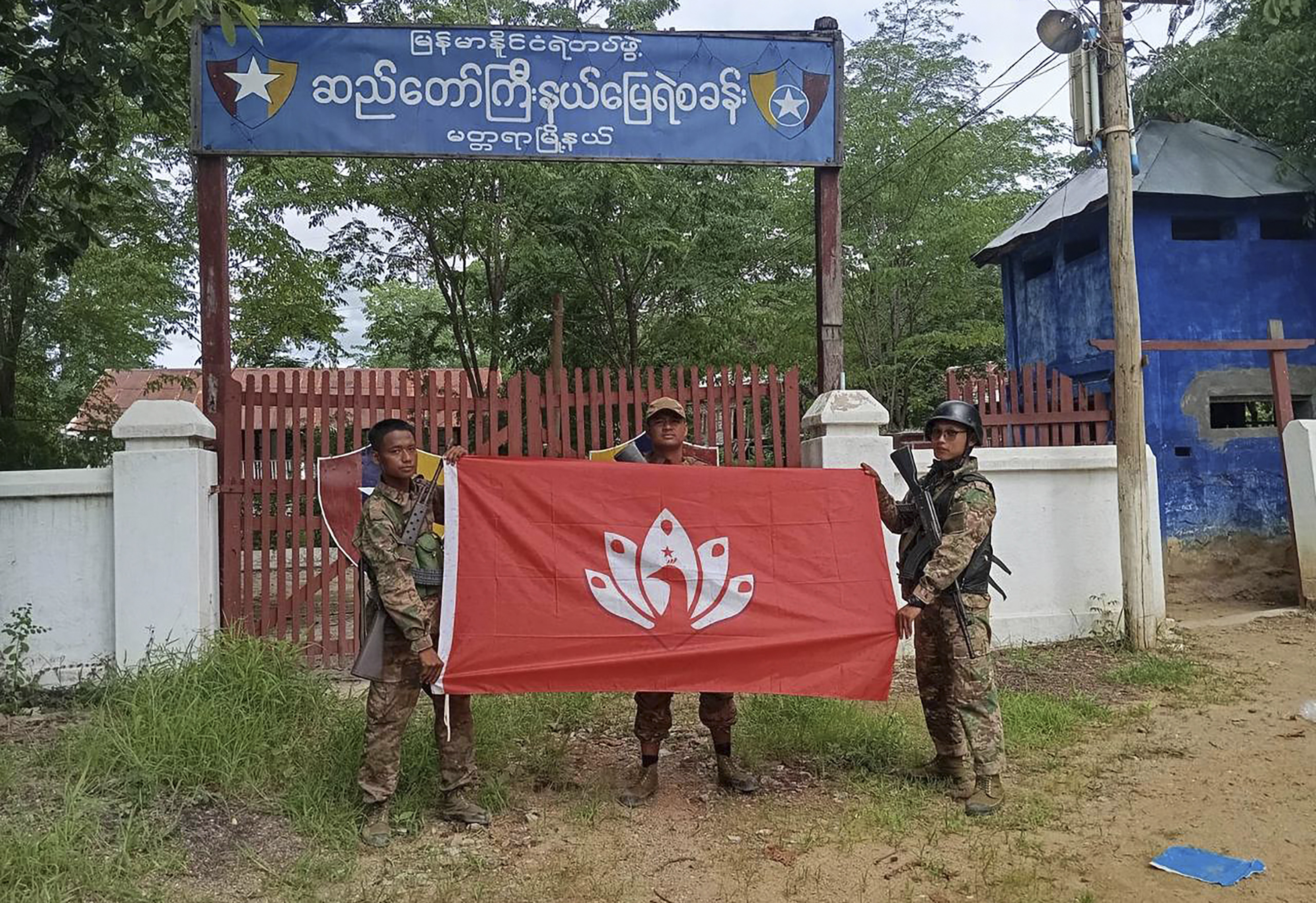 In this handout photo provided by Mandalay People's Defence Force, members of the Mandalay People's Defence Force pose for a photograph with the group's flag in front of the captured police station in Madaya township in Mandalay region, Myanmar, July 2, 2024. New fighting has broken out in northeastern Myanmar, bringing an end to a Chinese-brokered cease-fire and putting pressure on the military regime as it faces attacks from resistance forces on multiple fronts in the country's civil war. (Mandalay People's Defence Force via AP)