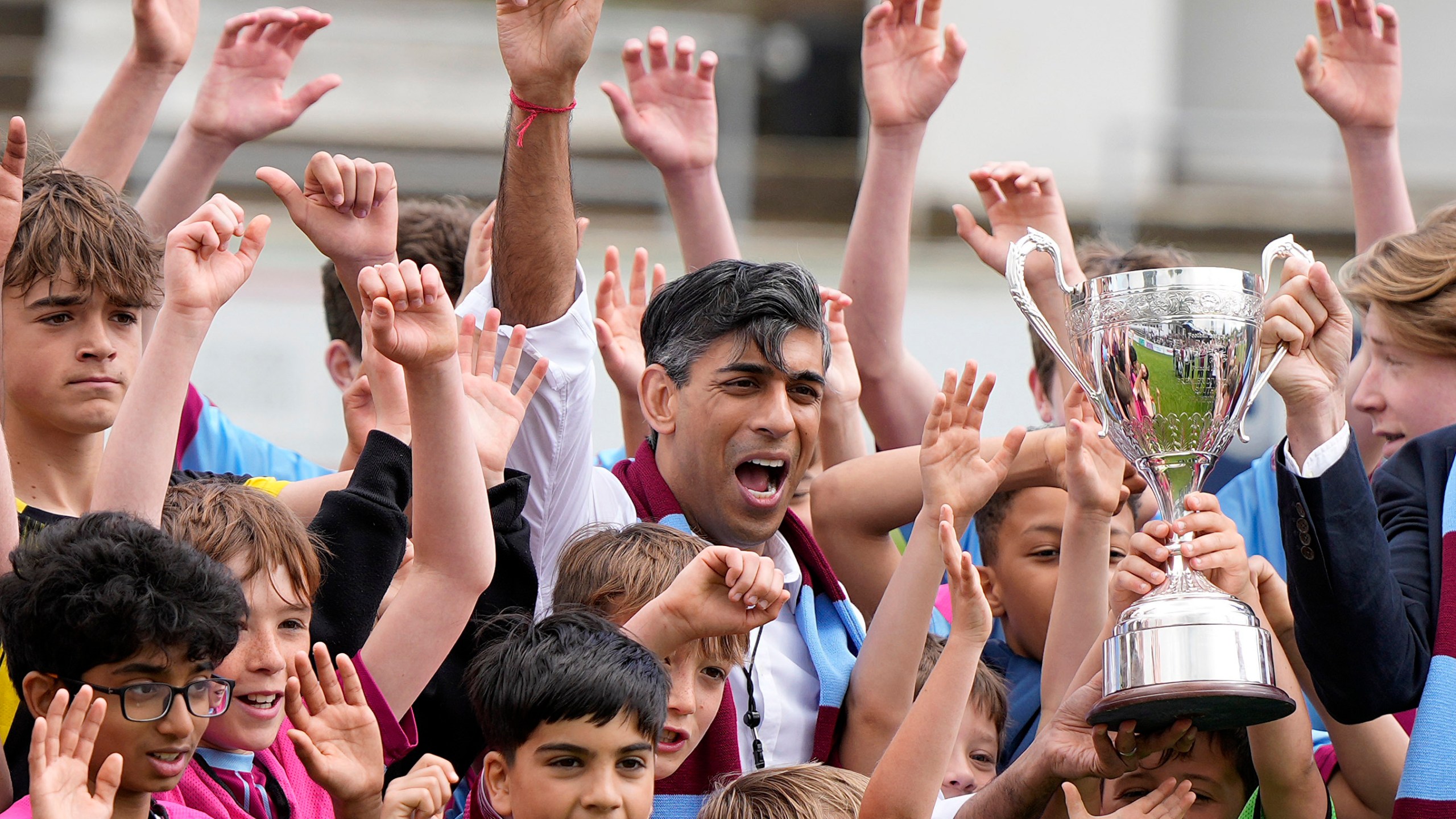 FILE - Britain's Prime Minister Rishi Sunak poses for a photo with children and a trophy as he joins the Chesham United Youth FC during a Conservative general election campaign event in Chesham, England, Monday, May 27, 2024.(AP Photo/Alastair Grant, Pool, File)