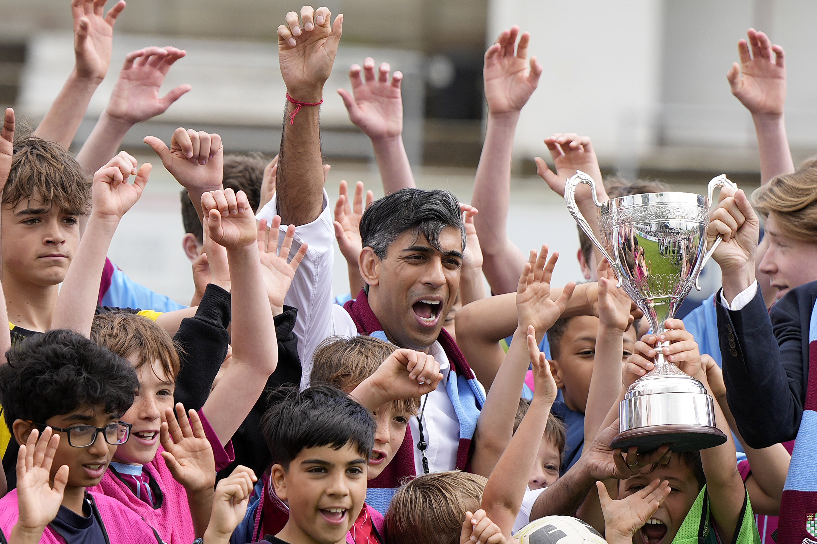 FILE - Britain's Prime Minister Rishi Sunak poses for a photo with children and a trophy as he joins the Chesham United Youth FC during a Conservative general election campaign event in Chesham, England, Monday, May 27, 2024.(AP Photo/Alastair Grant, Pool, File)