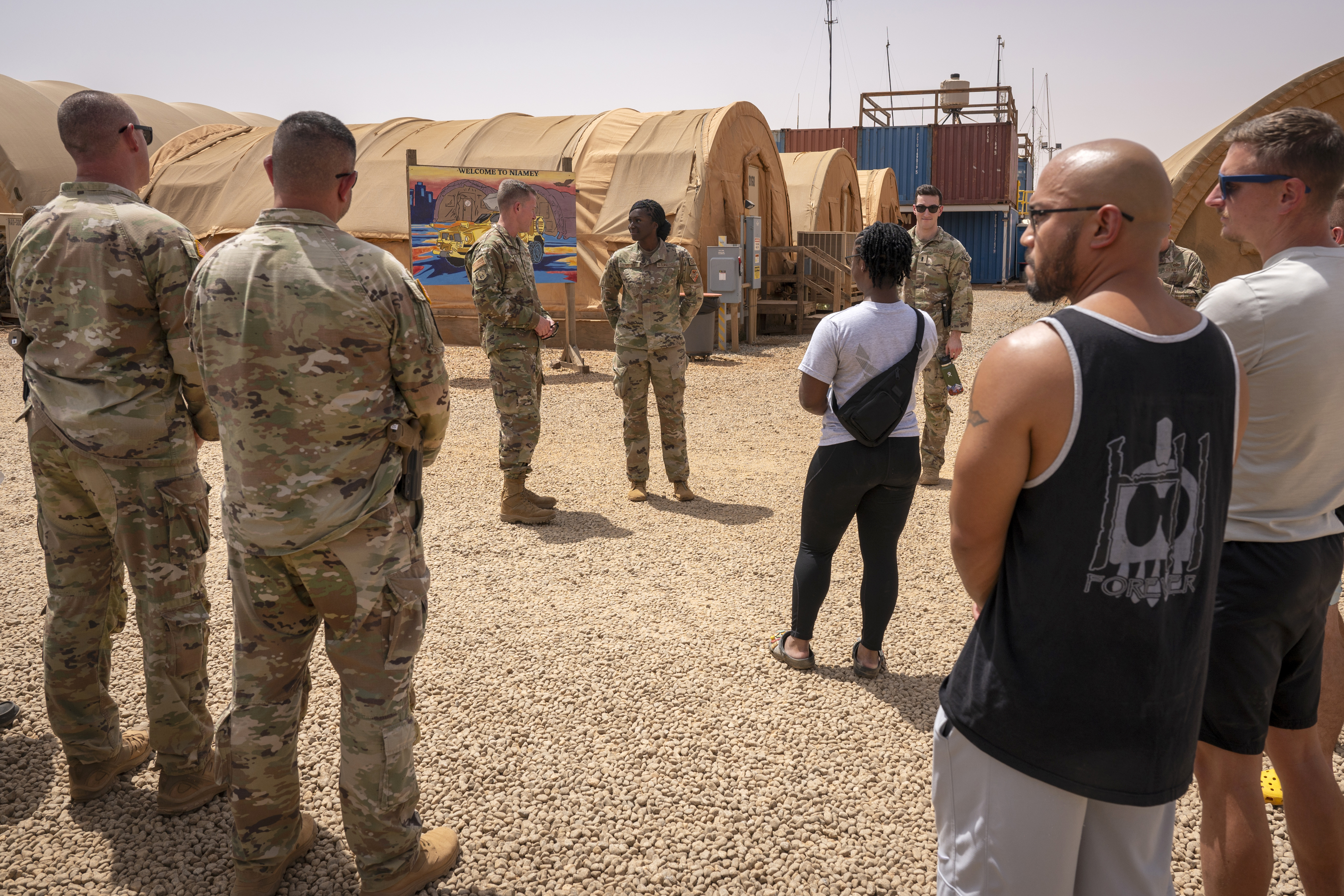 In this image by the U.S. Air Force, Maj. Gen. Kenneth P. Ekman speaks to military members in front of a "Welcome to Niamey" sign depicting U.S. military vehicles at Air Base 101 in Niger, May 30, 2024. Ekman the U.S. military commander in Niger, says all American forces and equipment will leave a smaller base in the West African country this weekend and fewer than 500 remaining troops will be out of a critical drone base in August. (Tech. Sgt. Christopher Dyer, U.S. Air Force via AP)