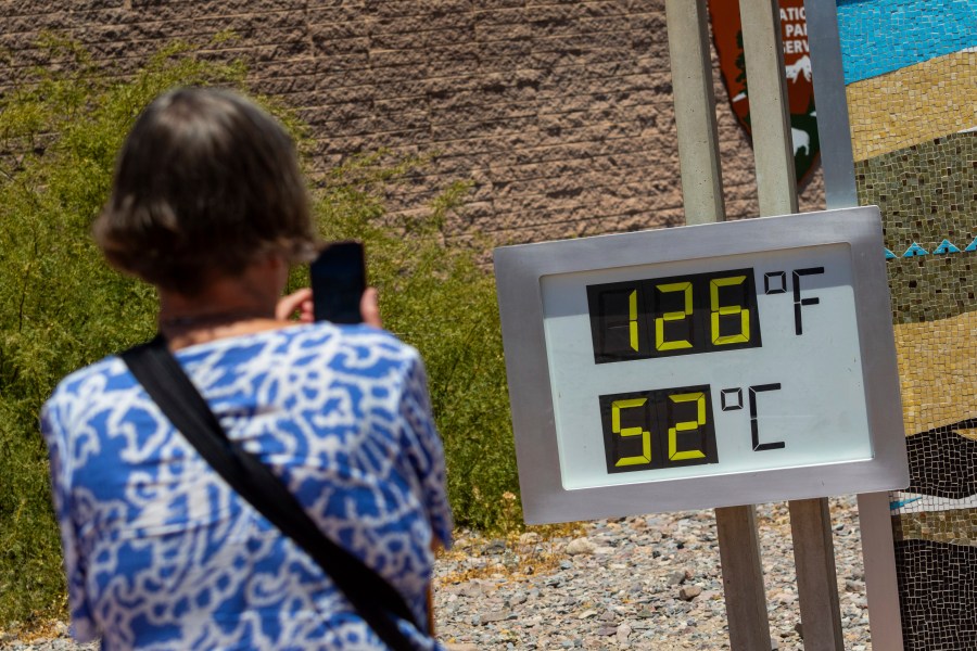 A woman takes a photo of a thermostat reading 126 degrees Fahrenheit and 52 degrees Celsius at the Furnace Creek Visitors Center in Death Valley National Park, Calif., Sunday, July 7, 2024. Forecasters say a heat wave could break previous records across the U.S., including in Death Valley. (AP Photo/Ty ONeil)