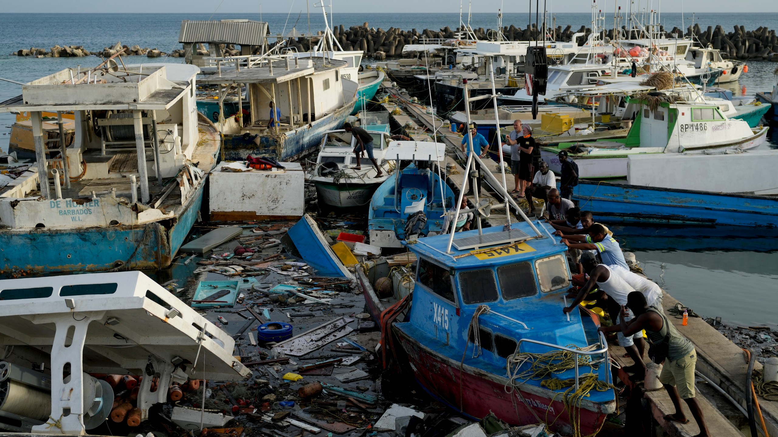 FILE - Fishermen push a boat damaged by Hurricane Beryl at the Bridgetown fisheries, Barbados, Tuesday, July 2, 2024. (AP Photo/Ricardo Mazalan, File)