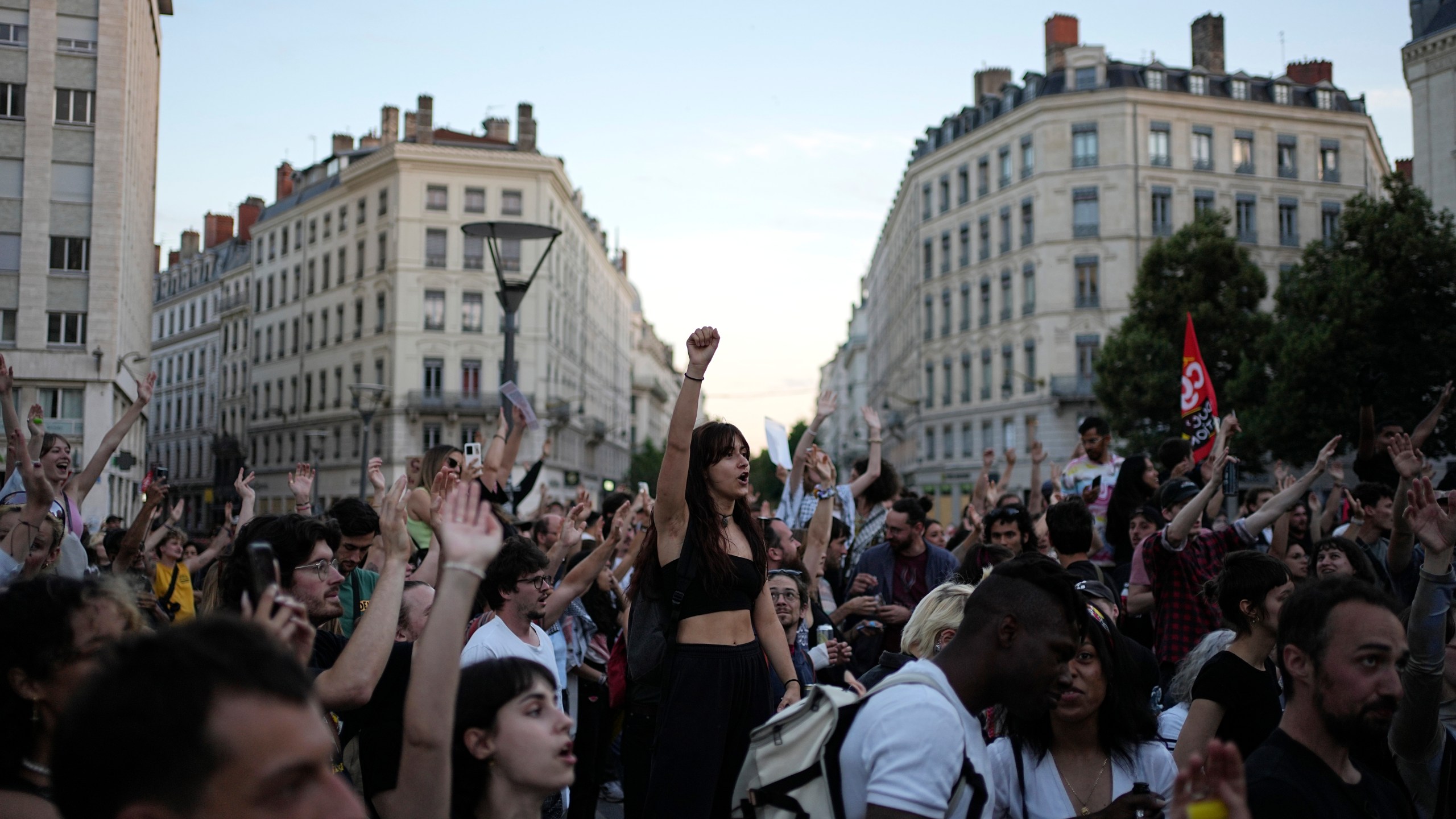 People stand in a square as they react to projected results after the second round of the legislative elections, in Lyon, central France, Sunday, July 7, 2024. Polls have closed in France, and polling projections say a coalition on the left that came together unexpectedly has won the most parliamentary seats in the pivotal runoff elections after a high turnout among voters. (AP Photo/Laurent Cipriani)