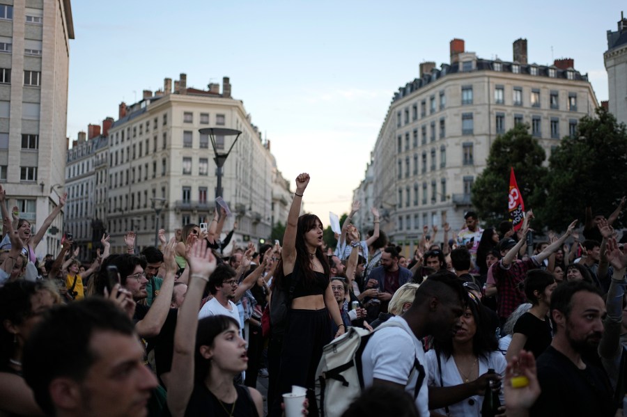 People stand in a square as they react to projected results after the second round of the legislative elections, in Lyon, central France, Sunday, July 7, 2024. Polls have closed in France, and polling projections say a coalition on the left that came together unexpectedly has won the most parliamentary seats in the pivotal runoff elections after a high turnout among voters. (AP Photo/Laurent Cipriani)