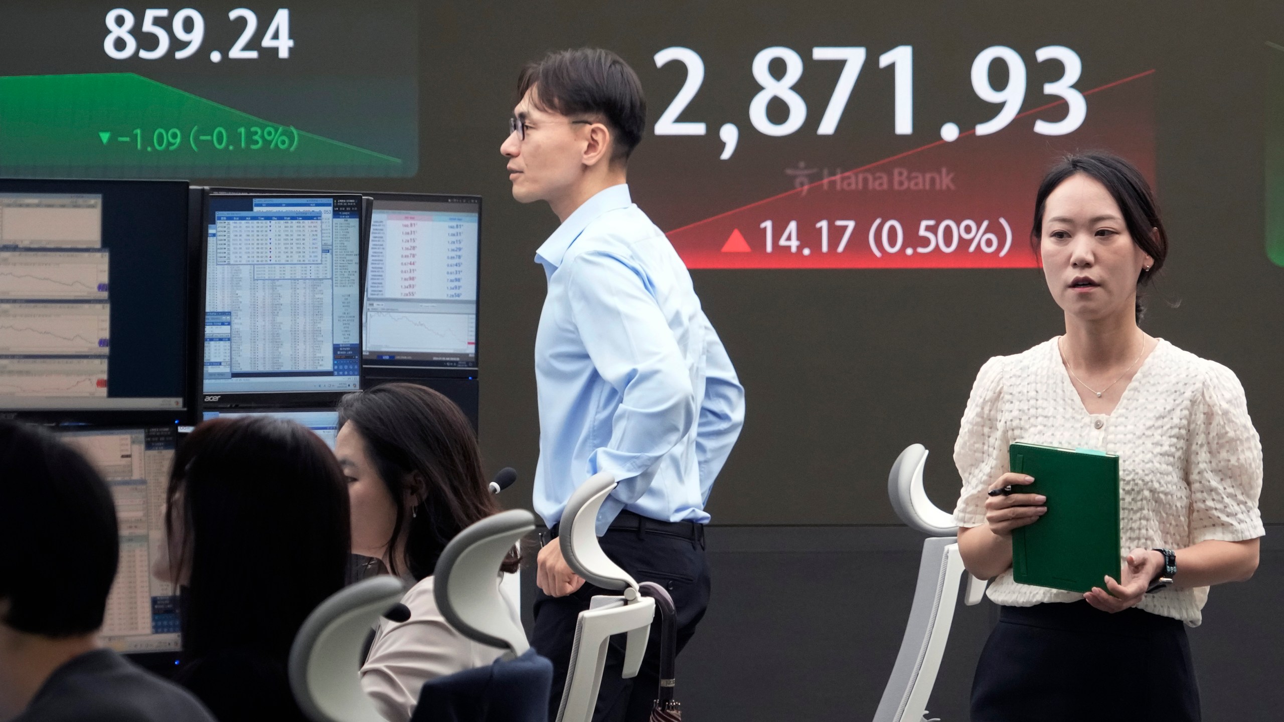 A currency trader passes by the screen showing the Korea Composite Stock Price Index (KOSPI) at the foreign exchange dealing room of the KEB Hana Bank headquarters in Seoul, South Korea, Tuesday, July 9, 2024. (AP Photo/Ahn Young-joon)