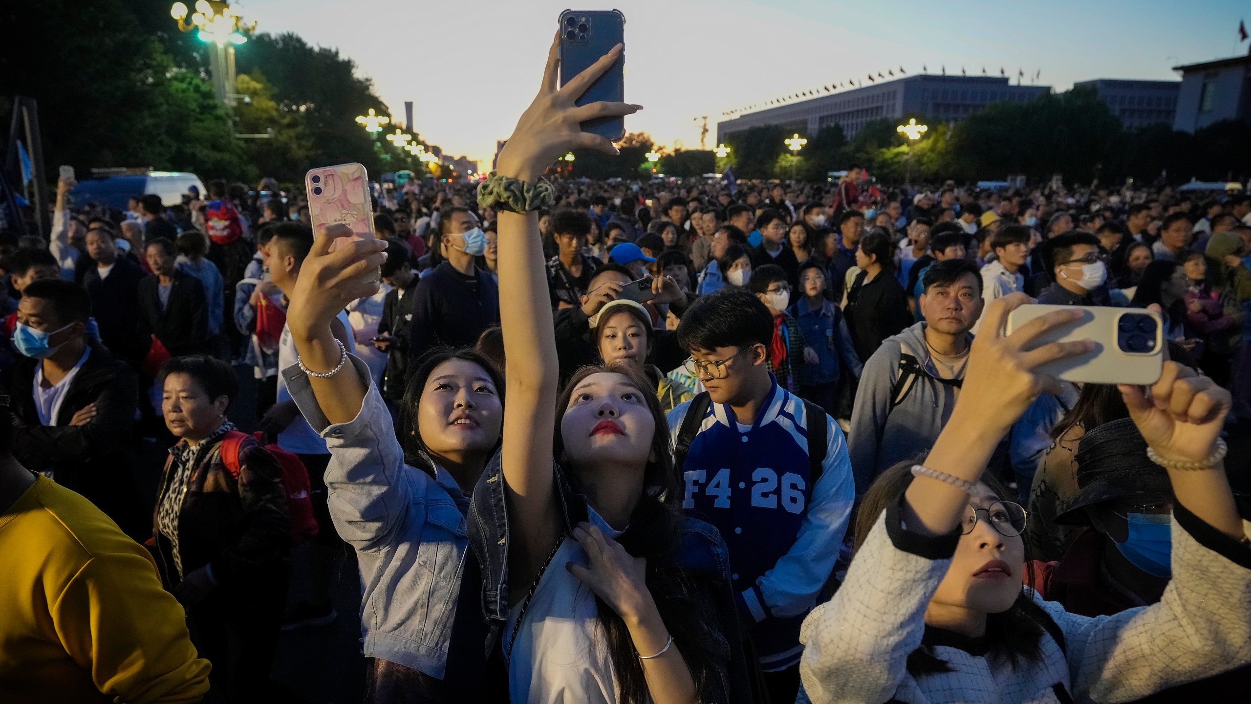 FILE - People take smartphone photos of the crowd on a street near Tiananmen Square as visitors gather to watch a flag-raising ceremony on the National Day in Beijing, Sunday, Oct. 1, 2023. The world’s population is expected to grow by more than 2 billion people in the next decades and peak in the 2080s at around 10.3 billion, a new report by the United Nations said Thursday July 11, 2024. (AP Photo/Andy Wong, File)