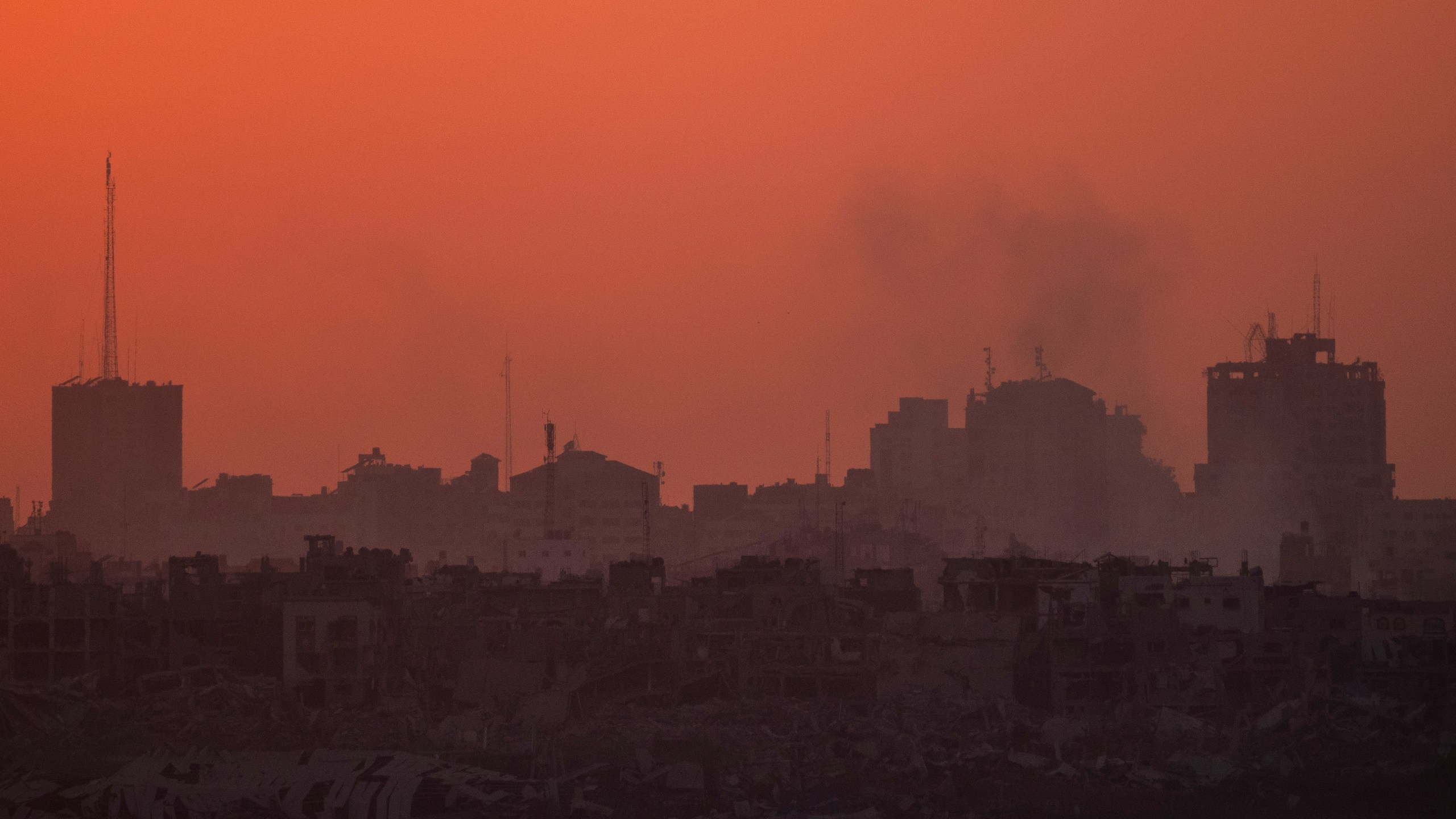 Destroyed buildings stand in the Gaza Strip during the sunset as seen from southern Israel, Wednesday, July 17, 2024. (AP Photo/Leo Correa)