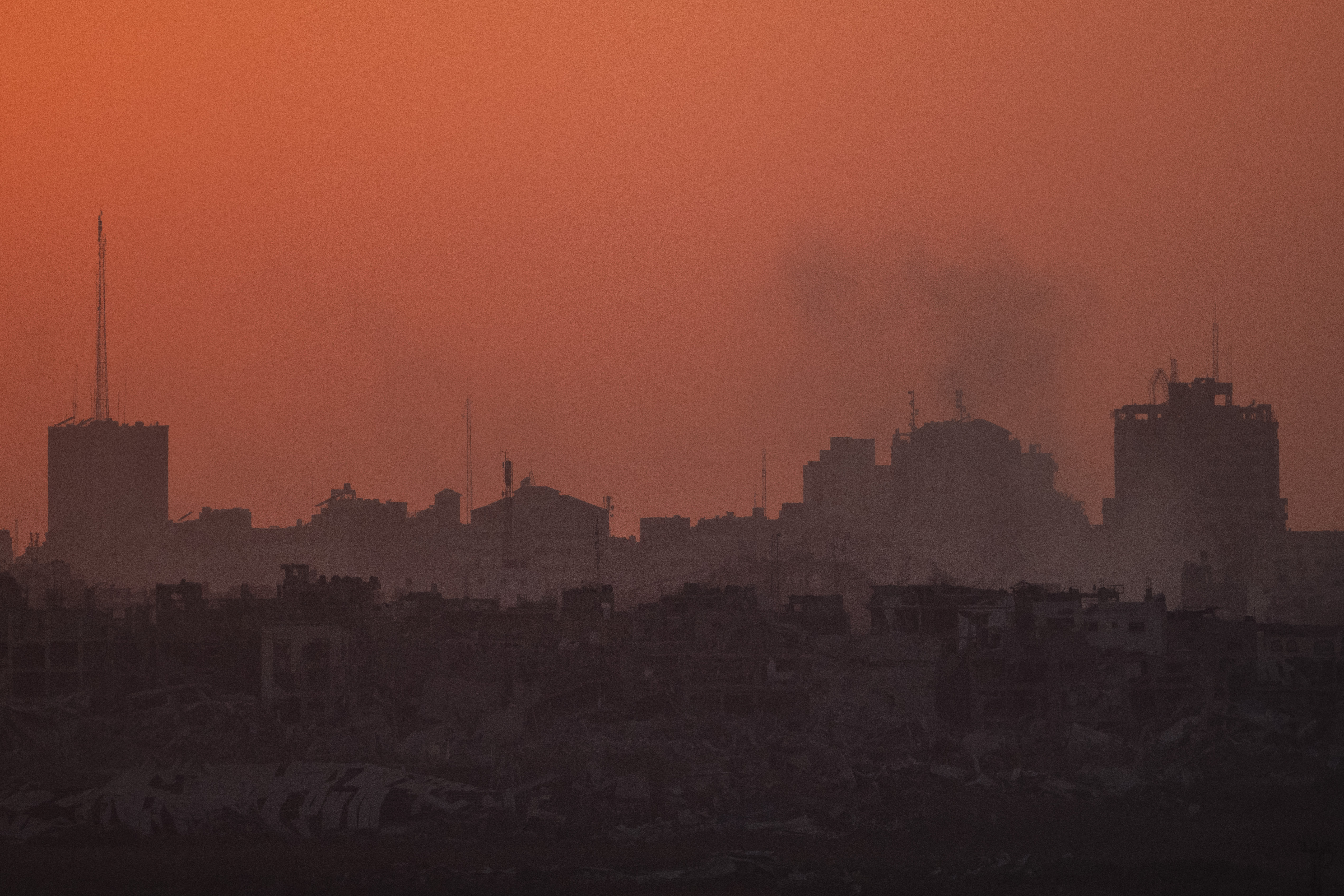 Destroyed buildings stand in the Gaza Strip during the sunset as seen from southern Israel, Wednesday, July 17, 2024. (AP Photo/Leo Correa)