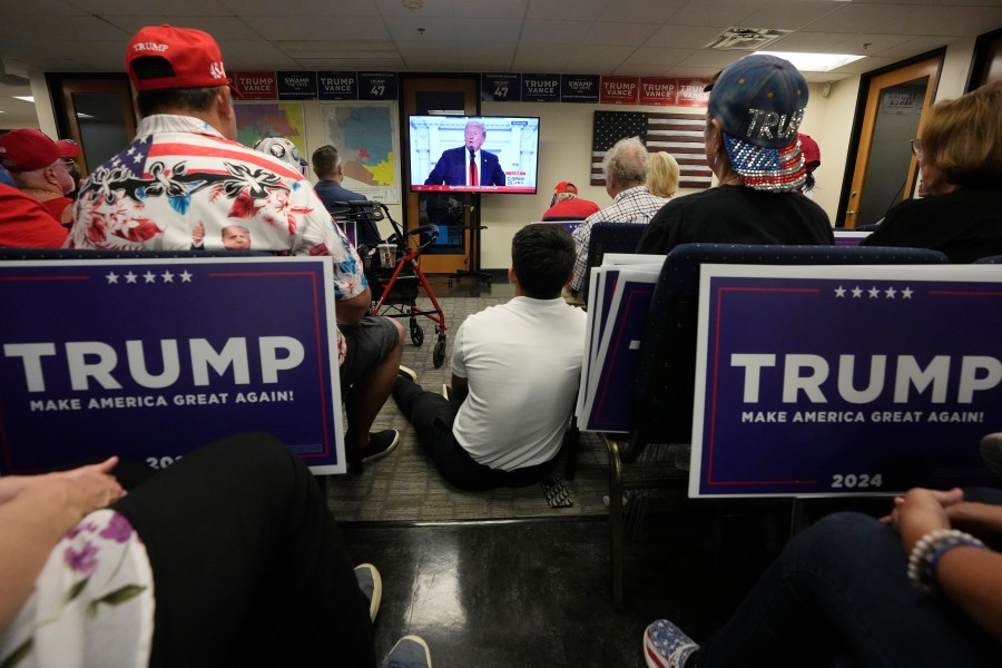 Supporters of Republican presidential candidate former President Donald Trump watch his speech at the Republican National Convention on a television from the Arizona GOP headquarters Thursday, July 18, 2024, in Phoenix. (AP Photo/Ross D. Franklin)