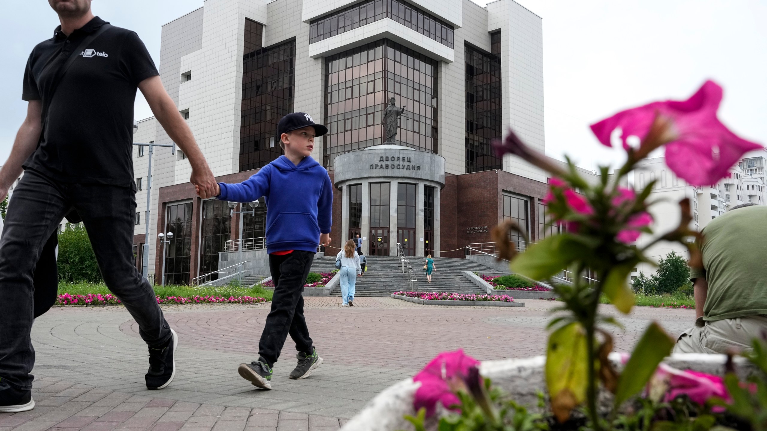 People walk past the court building with the words reading, "Palace of justice," on the front in Yekaterinburg, Russia, Friday, July 19, 2024, prior to the trial of Wall Street Journal reporter Evan Gershkovich's suspected spying activities. (AP Photo/Dmitri Lovetsky)