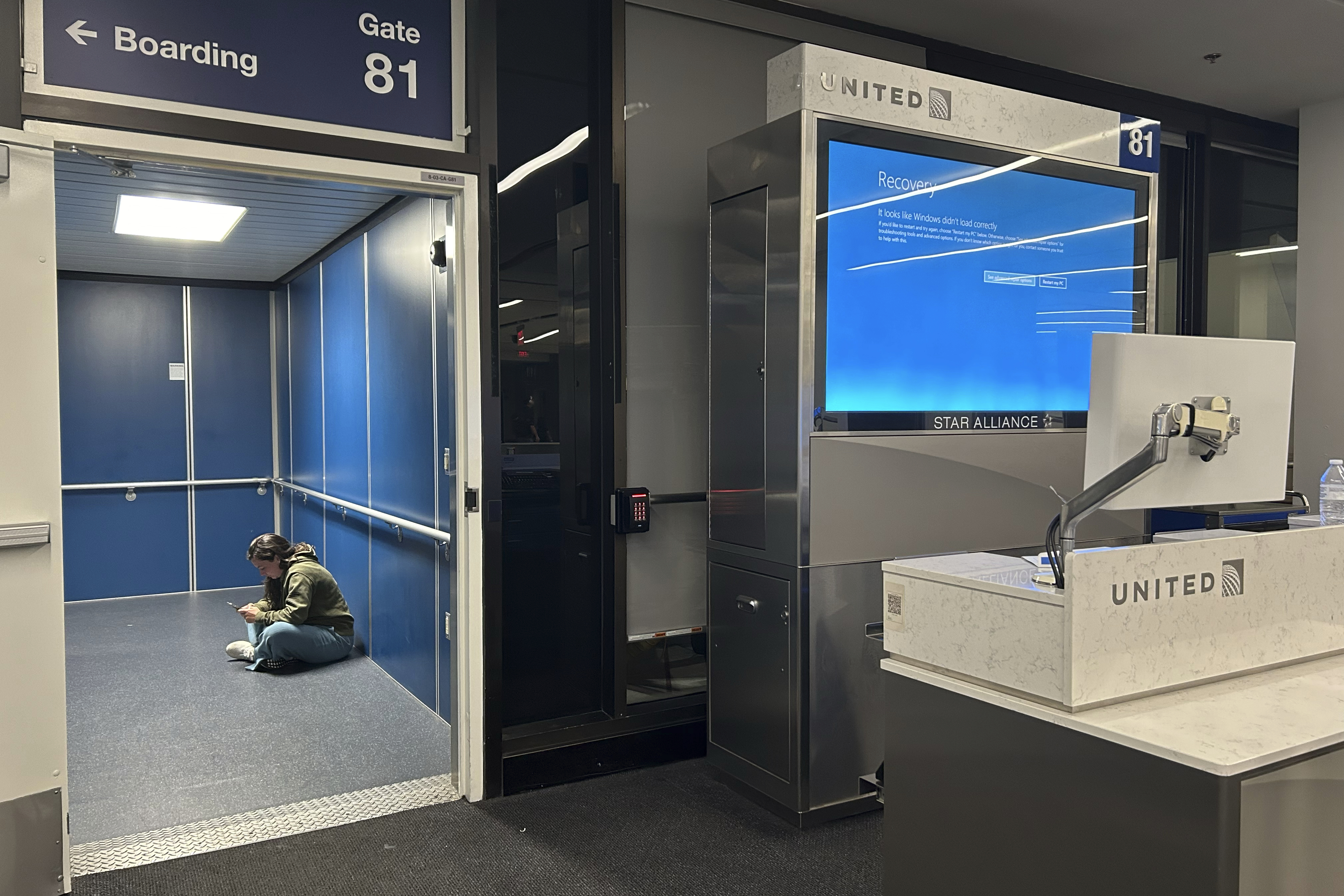 A traveler at Los Angeles International Airport sits in a jetway for a delayed United Airlines flight to Dulles International Airport due to a widespread global technology outage disrupting flights, banks, media outlets and companies around the world, Friday, July 19, 2024, in Los Angeles. (AP Photo/Stefanie Dazio)