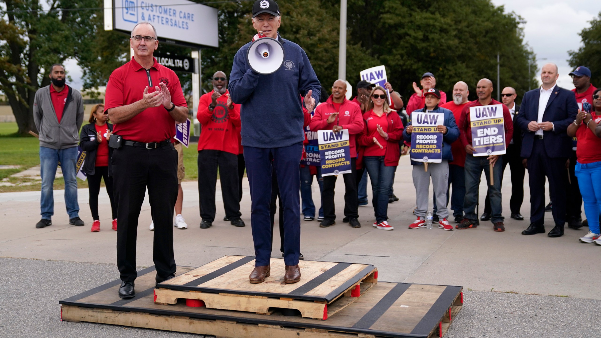 File - United Auto Workers President Shawn Fain, left, listens as President Joe Biden speaks to striking UAW members outside a General Motors facility on Sept. 26, 2023, in Van Buren Township, Mich. Donald Trump made a pitch for votes from key swing state autoworkers during his speech at the Republican National Convention, using false claims to call on them to fire Fain. (AP Photo/Evan Vucci, File)