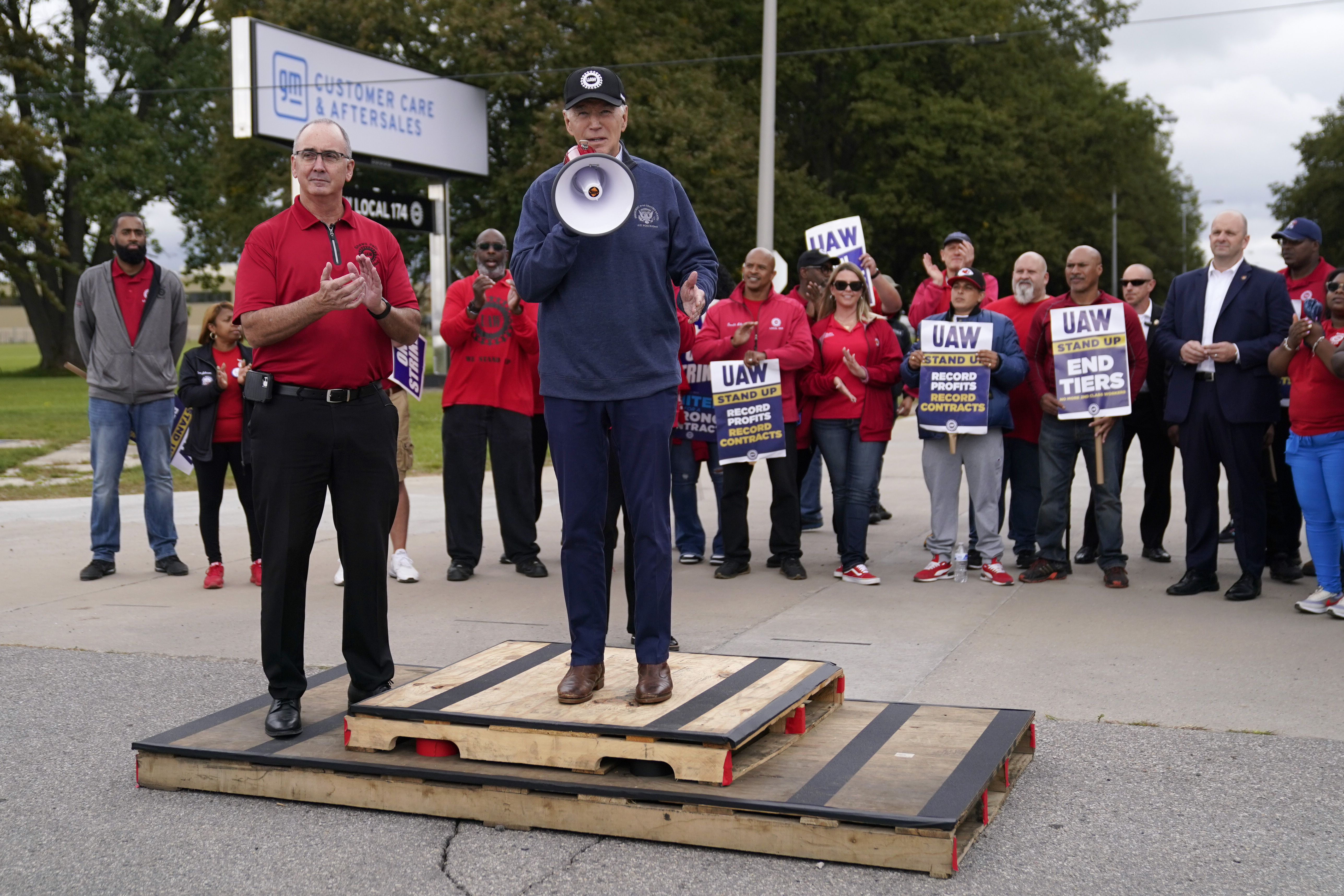 File - United Auto Workers President Shawn Fain, left, listens as President Joe Biden speaks to striking UAW members outside a General Motors facility on Sept. 26, 2023, in Van Buren Township, Mich. Donald Trump made a pitch for votes from key swing state autoworkers during his speech at the Republican National Convention, using false claims to call on them to fire Fain. (AP Photo/Evan Vucci, File)