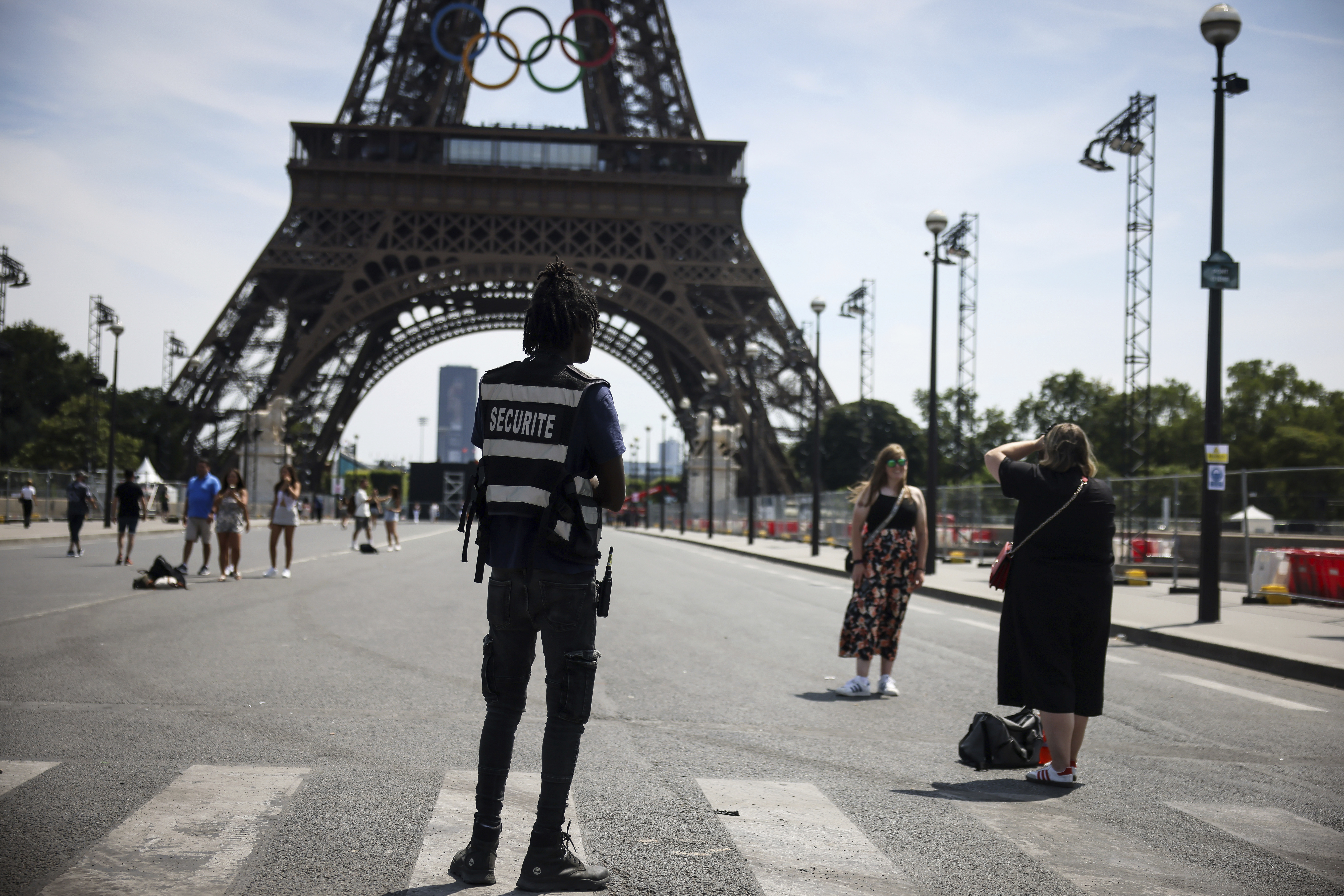 A security officer watches people taken photographs in front of the Eiffel Tower at the 2024 Summer Olympics, Saturday, July 20, 2024, in Paris, France. (AP Photo/Thomas Padilla)