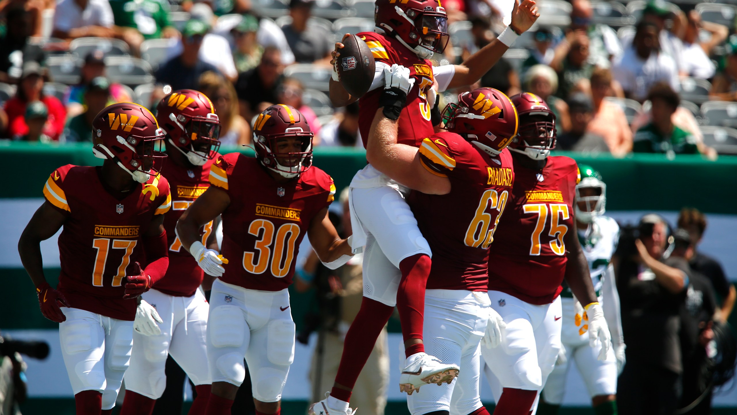 Washington Commanders quarterback Jayden Daniels (5) is congratulated by teammate Tyler Biadasz (63) after scoring during the first half of an NFL preseason football game against the New York Jets Saturday, Aug. 10, 2024, in East Rutherford. N.J. (AP Photo/John Munson)