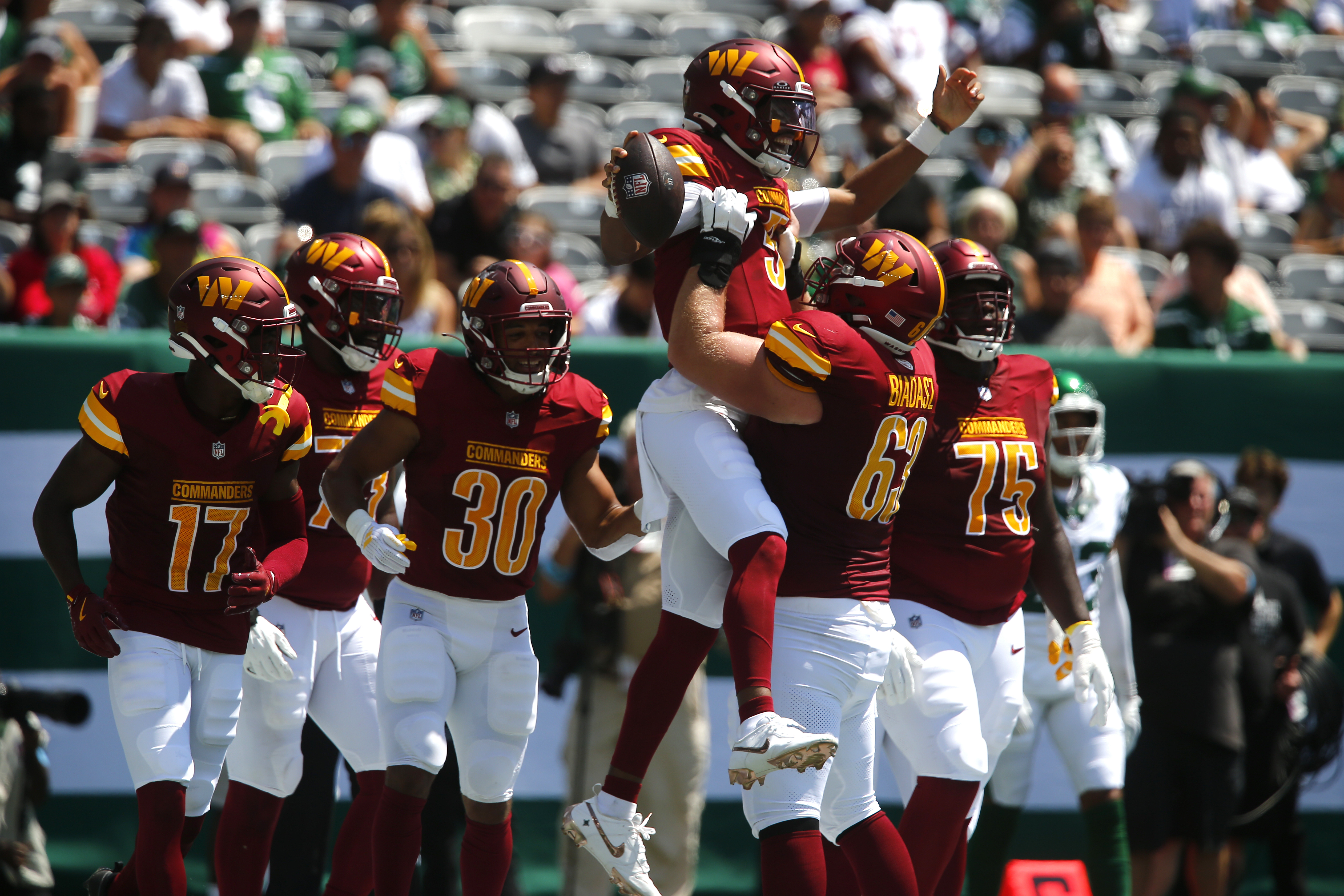 Washington Commanders quarterback Jayden Daniels (5) is congratulated by teammate Tyler Biadasz (63) after scoring during the first half of an NFL preseason football game against the New York Jets Saturday, Aug. 10, 2024, in East Rutherford. N.J. (AP Photo/John Munson)