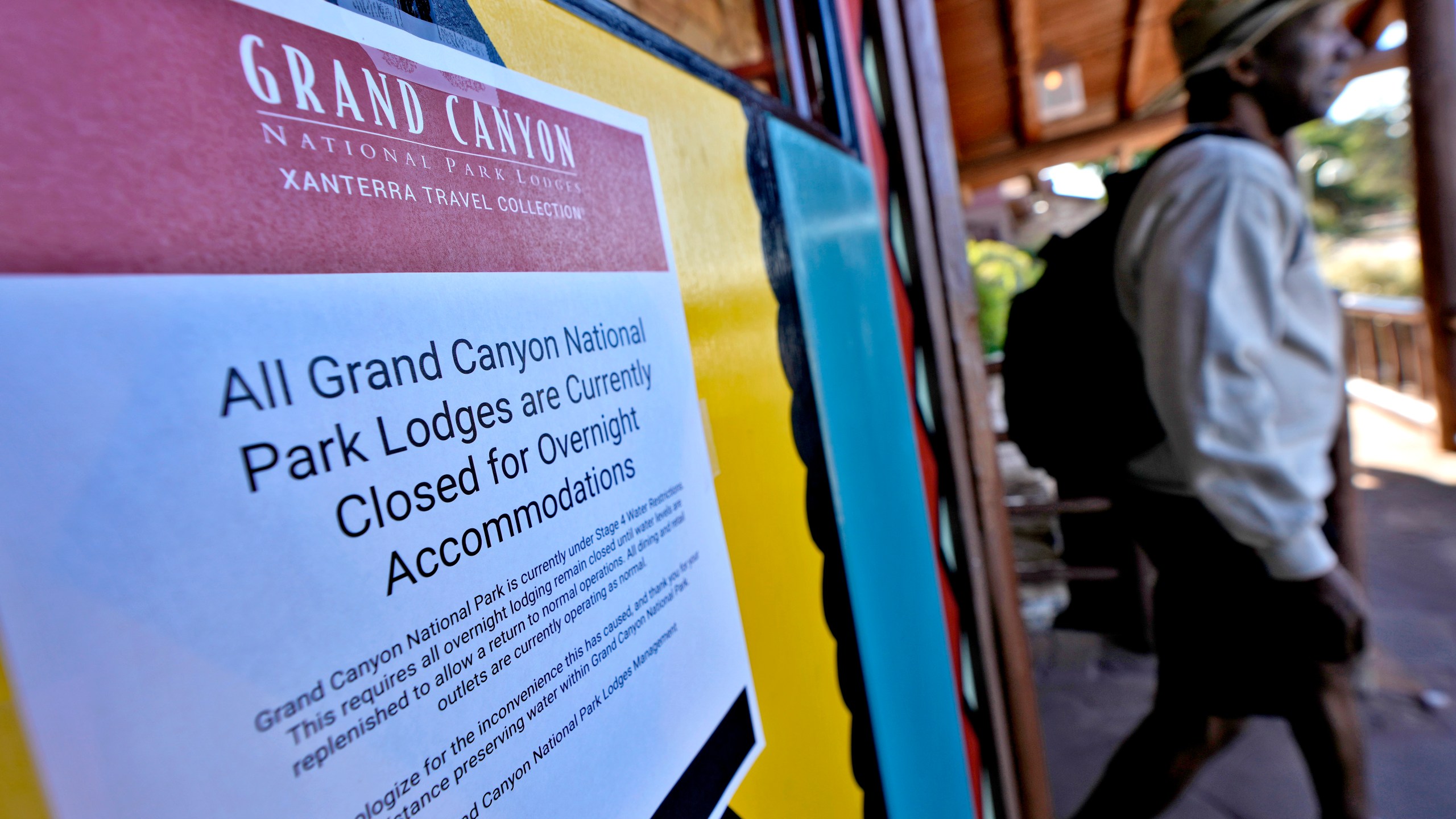 A sign denoting park lodge closures hangs on the door as a guest exits the Bright Angel Lodge, Thursday, Aug. 29, 2024, in Grand Canyon, Ariz. (AP Photo/Matt York)