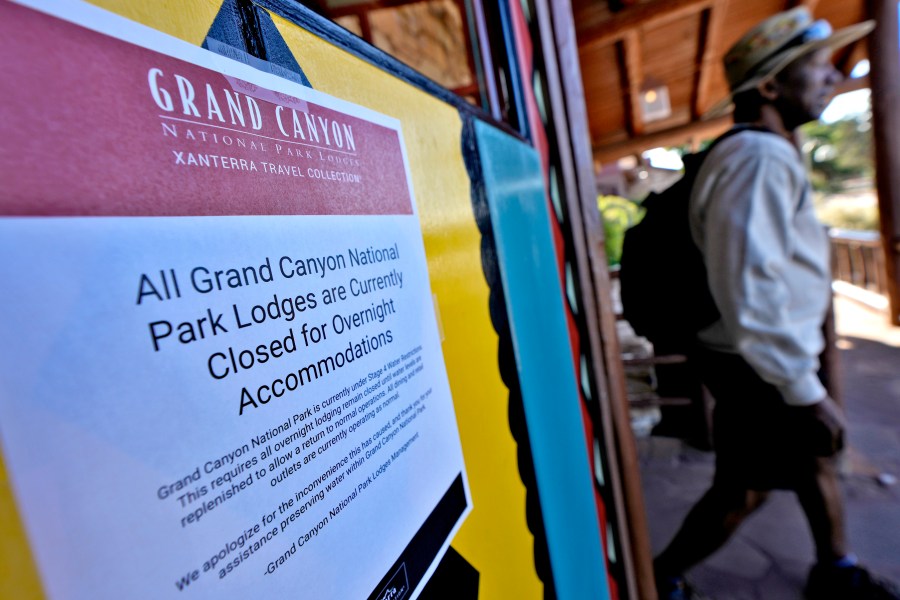 A sign denoting park lodge closures hangs on the door as a guest exits the Bright Angel Lodge, Thursday, Aug. 29, 2024, in Grand Canyon, Ariz. (AP Photo/Matt York)