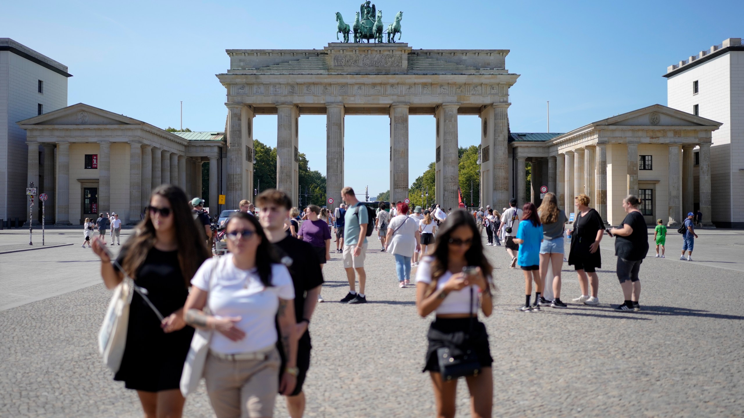 People stand in front of Berlin's famous landmark 'Brandenburg Gate' in Berlin, Germany, Monday, Sept. 2, 2024. (AP Photo/Markus Schreiber)